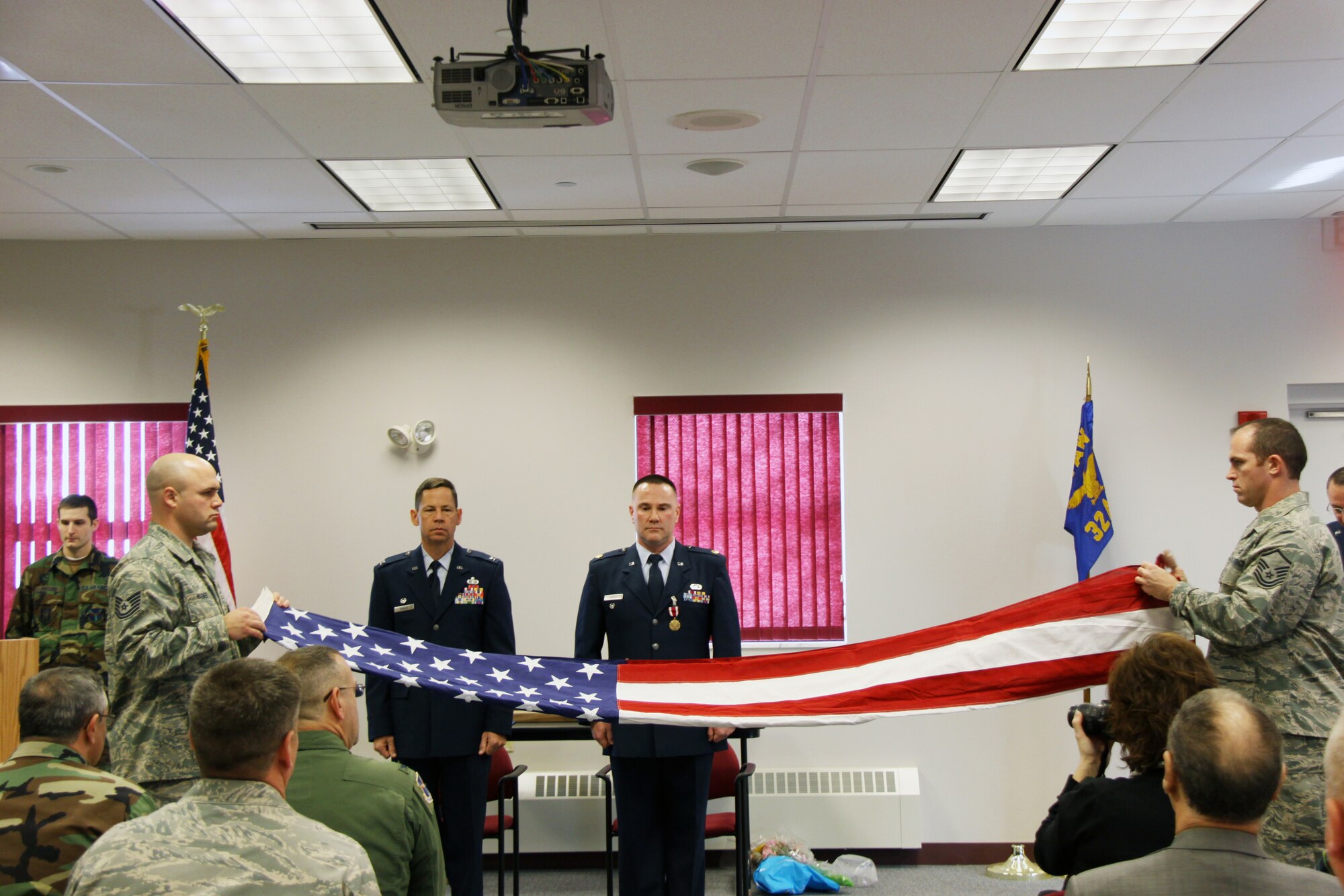 A retirement ceremony was held at the 911th Airlift Wing, 32nd Aerial Port Squadron, Jan. 9, 2010, for Maj. Paul J. Hurley (right).  Maj. Hurley began his military career as an enlisted member, moving through the ranks to technical sergeant before being commissioned second lieutenant in April 1993. As an officer he obtained the rank of major with 24-year's military service. Presiding over the ceremony was Col. James B. Hurley (left, no relation to the major), 911 AW Mission Support Group commander. A flag folding was part of the ceremony. (Left) Holding the flag is Tech. Sgt. Matthew Wagner. (Right) Folding the flag is Master Sgt. Dennis Jendrzejewski.  Both are air transportation specialists for the 32 APS.  Chief Master Sgt. Joseph McArthur, chief, 32 APS port operations, explained the meaning behind every fold.  The flag was then given to the retiree.