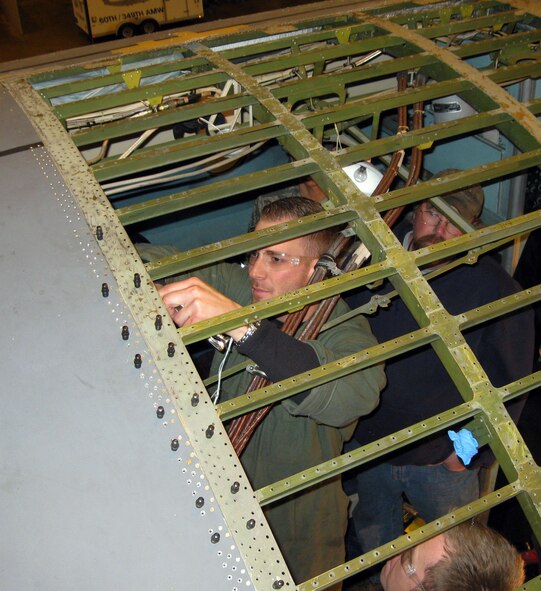 Staff Sgt. Brent Dost, and Air Reserve technician with the 349th Maintenance Squadron, works on a C-5C with, right, Staff Sgt. Dan Louden, 60th Maintenance Squadron, and Tom Chalmers, a Department of Defense civilian. What started out as a small repair on the aircraft grew into major repairs with the discovery and cracks underneath the "skin." This C-5C Galaxy, one of only two in Air Force inventory, is specially modified to support shuttle missions for NASA. Both aircraft are housed at Travis. (U.S. Air Force photo/Terry Hendrickson)