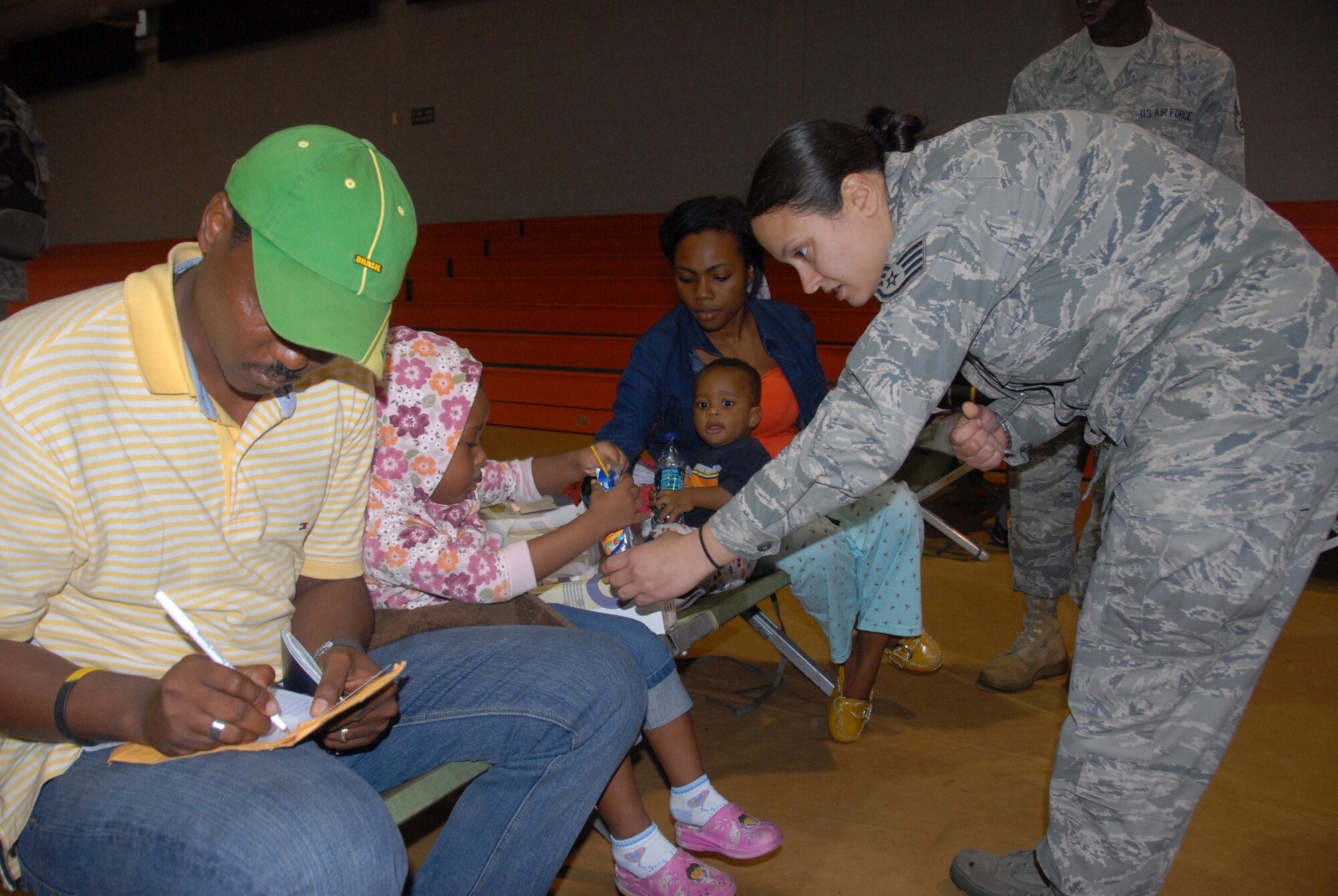 An Air Force Reservist from the 482nd Fighter Wing at Homestead Air Reserve Base, Fla., gives a drink to a young girl who arrived from Haiti Jan. 20, 2010. The girl and her family are being in-processed on base. Hundreds of evacuees have been in-processed so far and thousands more are expected. (Air Force photo/Master Sgt. Chance Babin)
