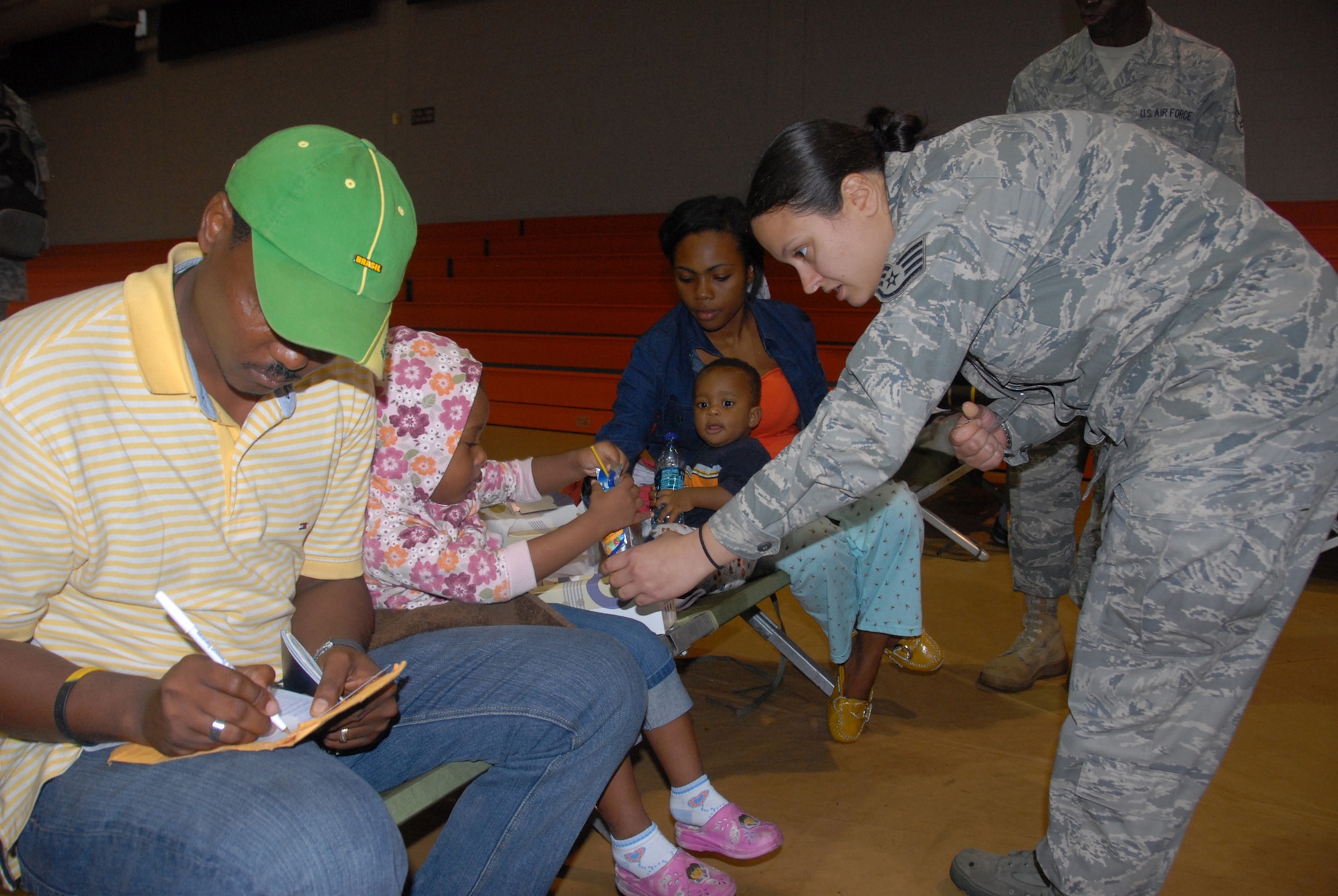 An Air Force Reservist from the 482nd Fighter Wing, gives a drink to a young girl recently transported from Haiti. The girl and her family are being in-processed on base. Hundreds of evacuees have been in-processed so far and thousands more are expected. (Air Force photo/Master Sgt. Chance Babin)