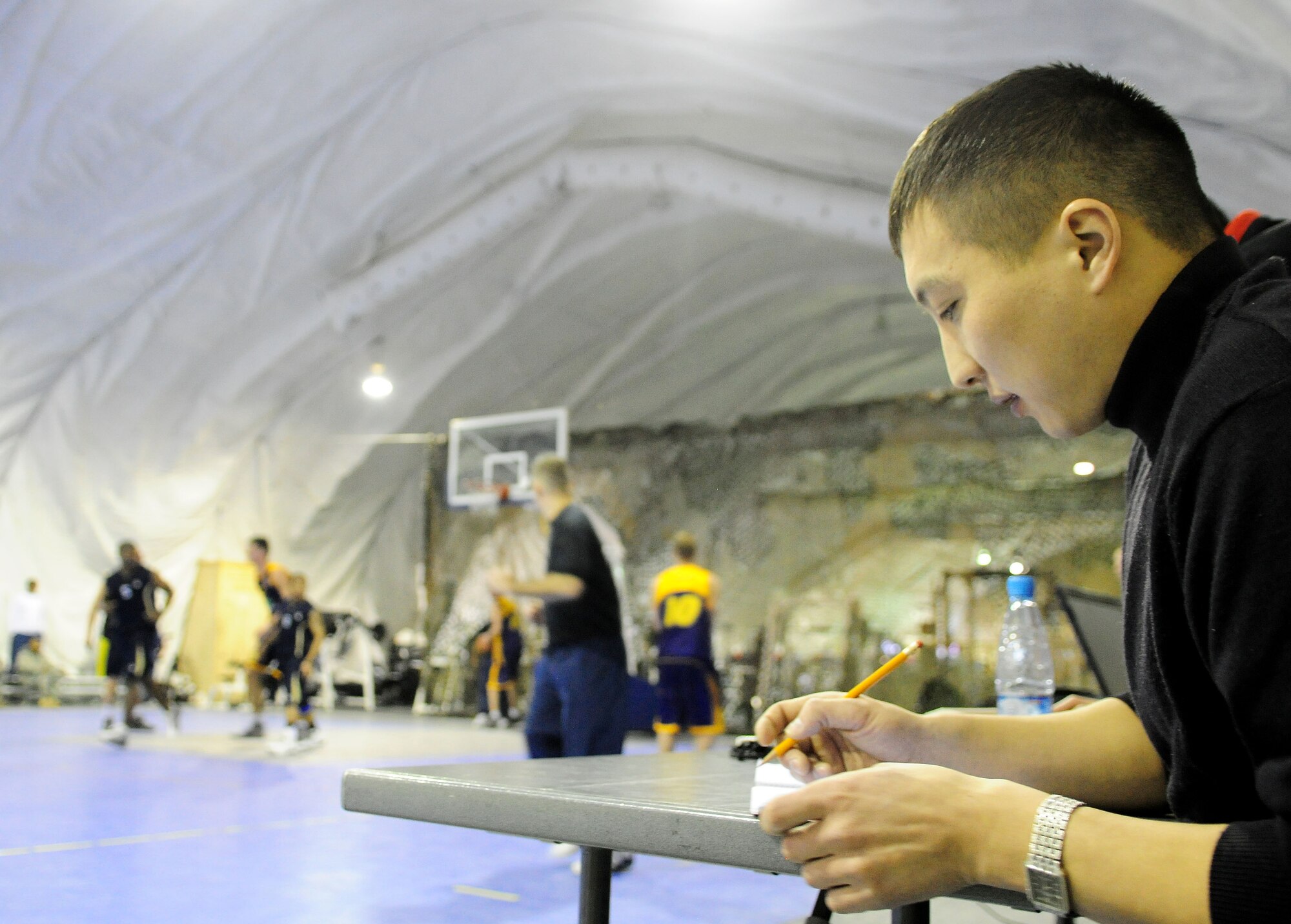 The Kyrgyz score keeper records statistics during a good will basketball game between U.S. Air Force members from the Transit Center at Manas, Kyrgyzstan and students of the Academy of Physical Culture and Sports, Jan. 19, 2010. The APCS defeated the TC team 72-55. (U.S. Air Force photo/Senior Airman Nichelle Anderson/released)