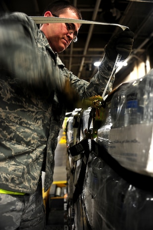 U.S. Air Force Airman 1st Class Jacob Preist, a cargo specialist with the 437th Aerial Port Squadron, 437th Airlift Wing, tightens the straps of a pallet of water bound for Haiti at Charleston Air Force Base (AFB), S.C., Jan. 16, 2010. So far, 56 pallets of water have been built and will be flown on C-17 Globemaster II aircraft to aid in the Haiti relief effort after a devastating earthquake struck the country Jan. 12, 2010. Charleston AFB is a component of Air Mobility Command (AMC). Since relief operations began Jan. 13, AMC aircraft have delivered more than 340 passengers and 323 tons of emergency cargo to Haiti. (U.S. Air Force photo by Staff Sgt. Ali E. Flisek/Released)