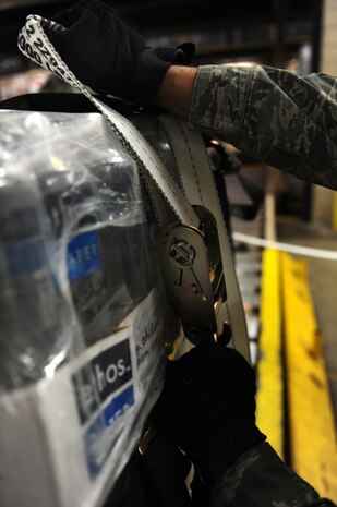 A U.S. Air Force cargo supervisor with the 437th Aerial Port Squadron, 437th Airlift Wing tightens the straps of a pallet of water bound for Haiti at Charleston Air Force Base (AFB), S.C., Jan. 16, 2010. So far, 56 pallets of water have been built and will be flown on C-17 Globemaster II aircraft to aid in the Haiti relief effort after a devastating earthquake struck the country Jan. 12, 2010. Charleston AFB is a component of Air Mobility Command (AMC). Since relief operations began Jan. 13, AMC aircraft have delivered more than 340 passengers and 323 tons of emergency cargo to Haiti. (U.S. Air Force photo by Staff Sgt. Ali E. Flisek/Released)