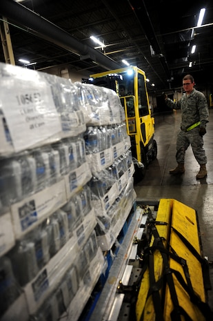 U.S. Air Force Airman 1st Class Jacob Preist, a cargo specialist from the 437th Aerial Port Squadron, 437th Airlift Wing, directs a forklift during the building of a pallet of water bound for Haiti at Charleston Air Force Base (AFB), S.C., Jan. 16, 2010. So far, 56 pallets of water have been built and will be flown on C-17 Globemaster II aircraft to aid in the Haiti relief effort after a devastating earthquake struck the country Jan. 12, 2010. Charleston AFB is a component of Air Mobility Command (AMC). Since relief operations began Jan. 13, AMC aircraft have delivered more than 340 passengers and 323 tons of emergency cargo to Haiti. (U.S. Air Force photo by Staff Sgt. Ali E. Flisek/Released)