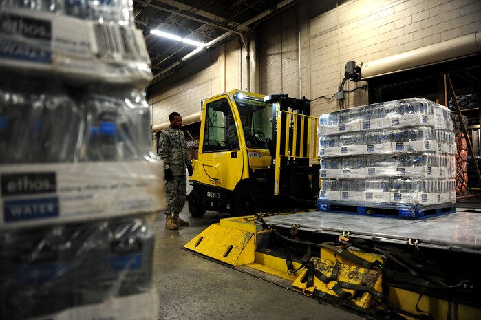 U.S. Air Force Airman 1st Class Eric Nicholson, left, and Senior Airman Richard Babbs, both cargo specialists from the 437th Aerial Port Squadron, 437th Airlift Wing, direct a forklift during the building of a pallet of water bound for Haiti at Charleston Air Force Base (AFB), S.C., Jan. 16, 2010. So far, 56 pallets of water have been built and will be flown on C-17 Globemaster II aircraft to aid in the Haiti relief effort after a devastating earthquake struck the country Jan. 12, 2010. Charleston AFB is a component of Air Mobility Command (AMC). Since relief operations began Jan. 13, AMC aircraft have delivered more than 340 passengers and 323 tons of emergency cargo to Haiti. (U.S. Air Force photo by Staff Sgt. Ali E. Flisek/Released) 
