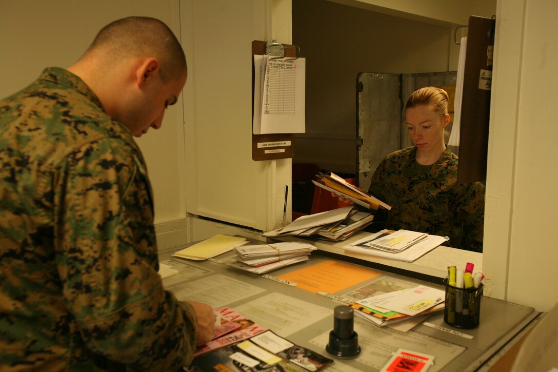 Lance Cpl. Timothy A. Wells, a postal clerk with the air station’s post office, sifts through mail to hand to Cpl. Audrey B. Ledbetter, mail clerk with Marine Wing Headquarters Squadron 2. The post office opened for military mail, Jan. 20 and will open for general purposes, Feb. 1.