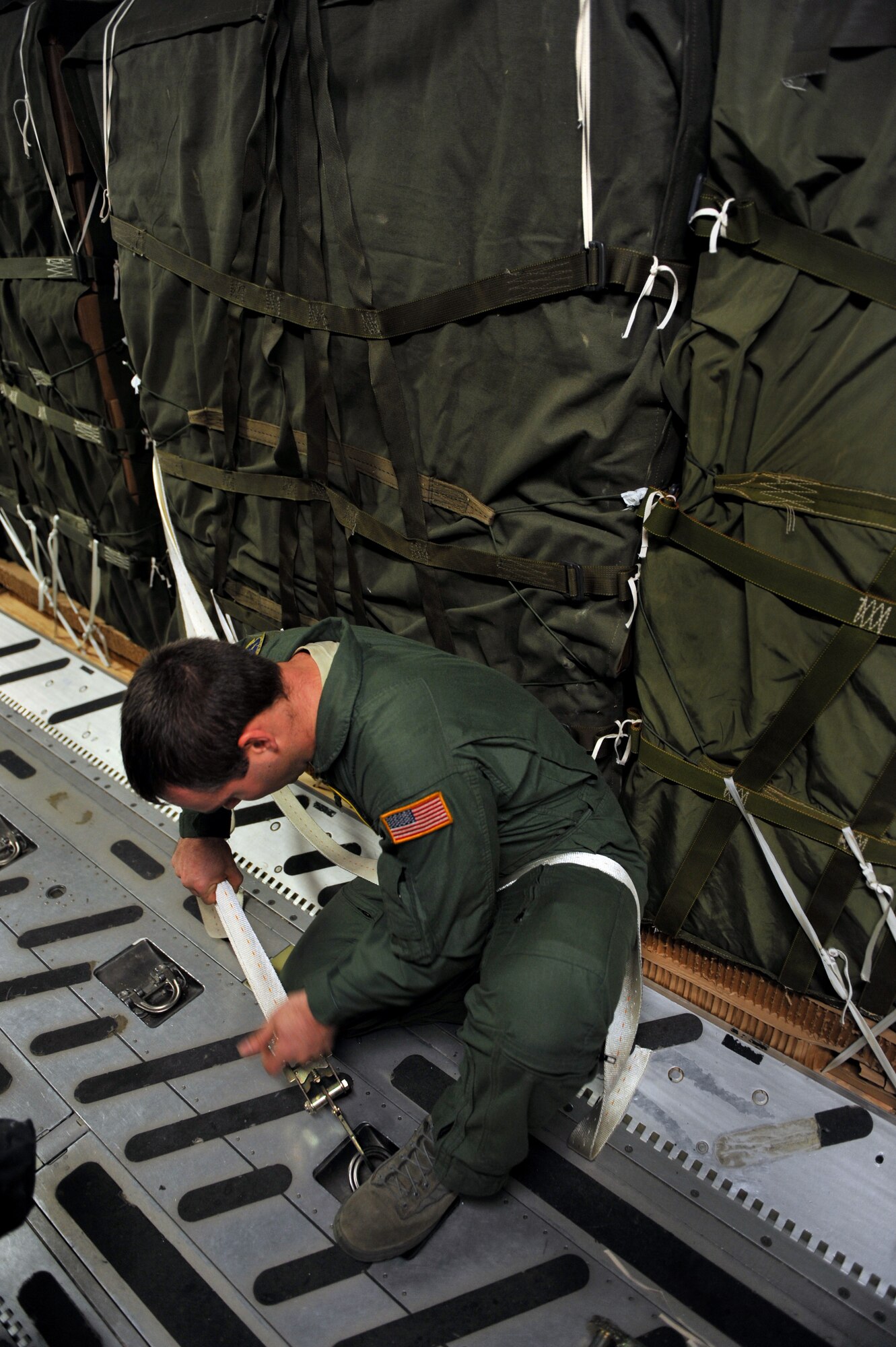 Staff Sgt. Joshua Walker attaches tie down straps to humanitarian supply pallets loaded on a C-17 Globemaster III Jan. 21, 2010, at Pope Air Force Base, Fayetteville, N.C. Sgt. Walker is a loadmaster from the 43rd Operations Support Squadron and is conducting a joint air delivery inspection on the pallets before they are air dropped over Haiti for a relief mission. The C-17, from Charleston Air Force Base, Charleston S.C., will be conducting a humanitarian air delivery mission over Haiti. U.S. Southern Command is deploying assets to Haiti to conduct search and rescue operations, damage assessments, and transitions sustained Humanitarian Assistance/Disaster Relief operations in order to prevent human suffering and additional loss of life. (U.S. Air Force photo/Master Sgt. Shane A. Cuomo) 
