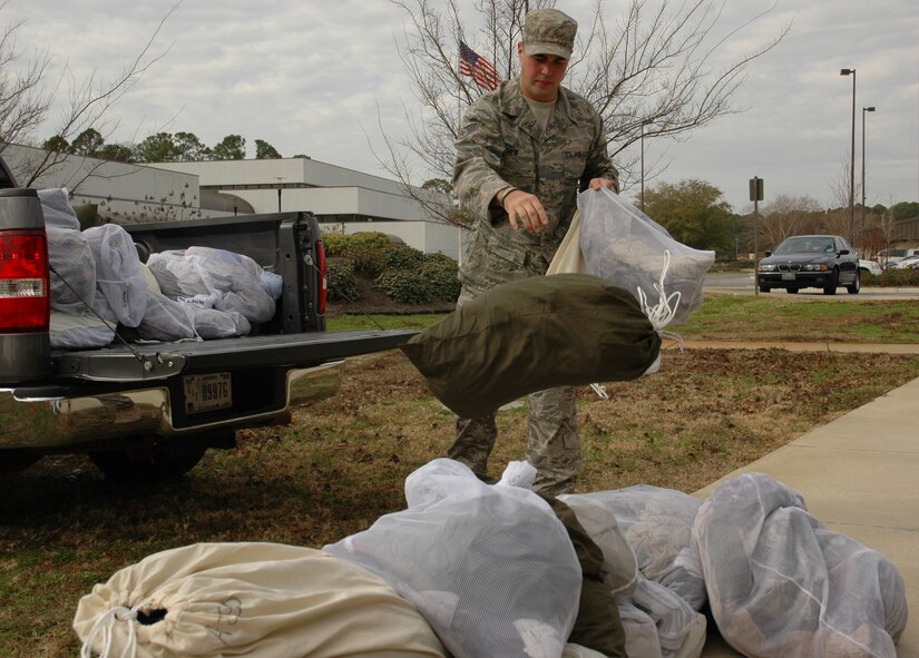 Senior Airman John New, 1st Special Operations Logistics Readiness Squadron, unloads bags of laundry belonging to Airmen deployed to Haiti outside the Hurlburt Field Airman & Family Readiness Center Jan. 20.  Volunteers washed the clothes at home before returning them to be loaded with supplies on a Haiti-bound C-130 later that night. (U.S. Air Force photo by Airman 1st Class Joe McFadden)