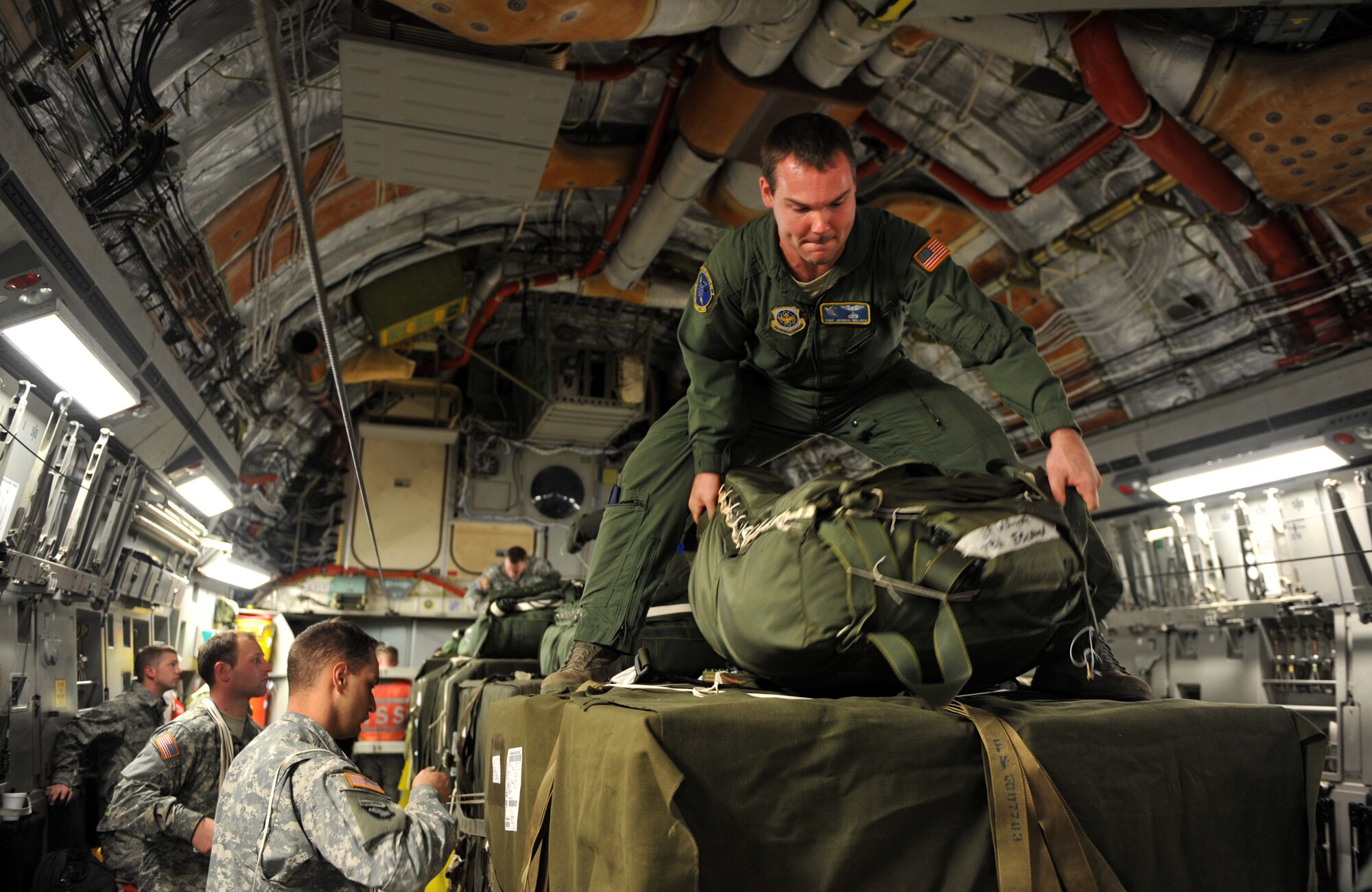 Staff Sgt. Joshua Walker readjusts a humanitarian supply pallet parachute Jan. 21, 2010, loaded on a C-17 Globemaster III at Pope Air Force Base, N.C. Sgt. Walker is a loadmaster from the 43rd Operations Support Squadron and is conducting a joint air delivery inspection on the pallets before they are air dropped over Haiti for a relief mission. The C-17, from Charleston Air Force Base, Charleston S.C., will be conducting a humanitarian air delivery mission over Haiti. U.S. Southern Command is deploying assets to Haiti to conduct search and rescue operations, damage assessments, and transitions sustained Humanitarian Assistance/Disaster Relief operations in order to prevent human suffering and additional loss of life. (U.S. Air Force photo/Master Sgt. Shane A. Cuomo) 