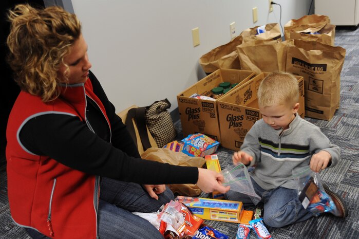 Leslie Mcnabb hands her son Noah snacks to load into a plastic bag on Charleston AFB, Jan. 21. The snacks will be taken by C-17 aircrews and will be used for evacuees being brought out of Haiti in support of the humanitarian relief effort. Leslie and Noah are the wife and son of Capt. Jarrett Mcnabb, the assistant director of operations with the 437th Operations Support Squadron. (U.S. Air Force photo/Senior Airman Katie Gieratz)(RELEASED) 


