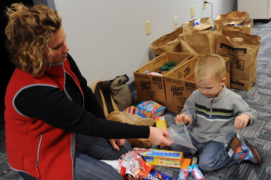 Leslie Mcnabb hands her son Noah a plastic bag to fill with snacks to load into a box on Charleston AFB, Jan. 21. The snacks will be taken by C-17 aircrews and will be used for evacuees being brought out of Haiti in support of the humanitarian relief effort. Leslie and Noah are the wife and son of Capt. Jarrett Mcnabb, the assistant director of operations with the 437th Operations Support Squadron. (U.S. Air Force photo/Senior Airman Katie Gieratz)(RELEASED) 
