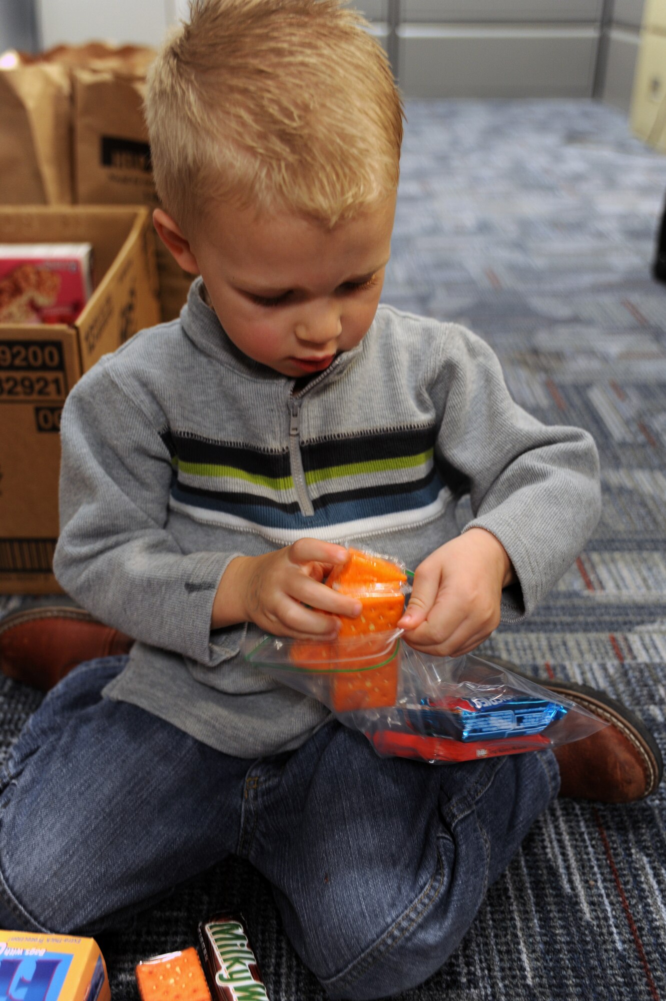 Noah Mcnabb loads snacks into a plastic bag at Charleston AFB, Jan. 21. The snack bags are for the evacuees that the C-17?s are bringing out of Haiti after the devastating earthquake. Noah is the son of Capt. Jarrett Mcnabb who is the assistant director of operations with the 437th Operations Support Squadron. (U.S. Air Force photo/Senior Airman Katie Gieratz)(RELEASED)

