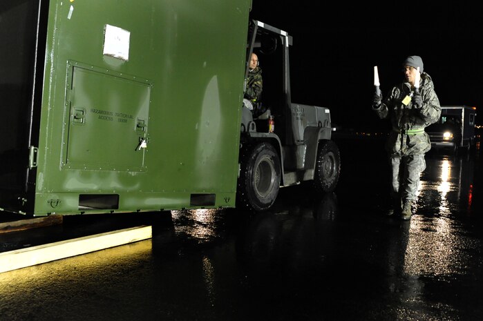 NELLIS AIR FORCE BASE, Nev.-- Airman 1st Class Troy Edwards uses flashlights to direct Senior Airman Jonathan Cantrell 99th Logistics Squadron where to move cargo in the cargo deployment function yard on Nellis Air Force Base as part of a 99th Air Base Wing operational readiness exercise Jan. 19. The ORE is in preparation for an upcoming operation readiness inspection Jan. 25-29. 
(U.S. Air Force photo by Tech. Sgt. Michael R. Holzworth)