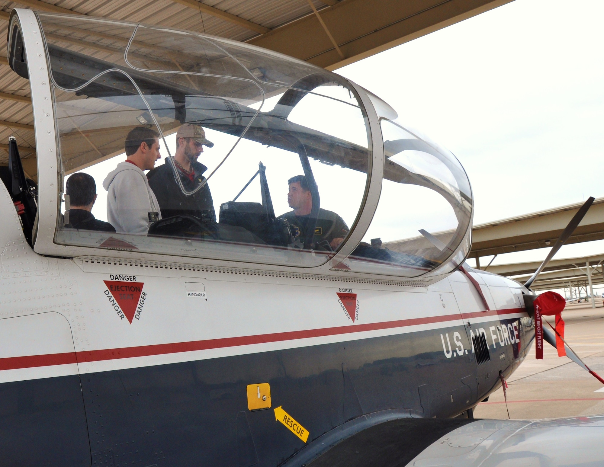 Maj. Steven Lygren, 80th Flying Training Wing commander’s action officer (front center), shows Doug Mathis (left) and Dustin Nippert (right), pitchers for the Texas Rangers, a T-6A Texan II, and explains interesting  facts about the aircraft. The two pitchers and part of the Texas Rangers staff visited Sheppard Jan. 20. (U.S. Air Force Photo / Airman 1st Class Adawn Kelsey)