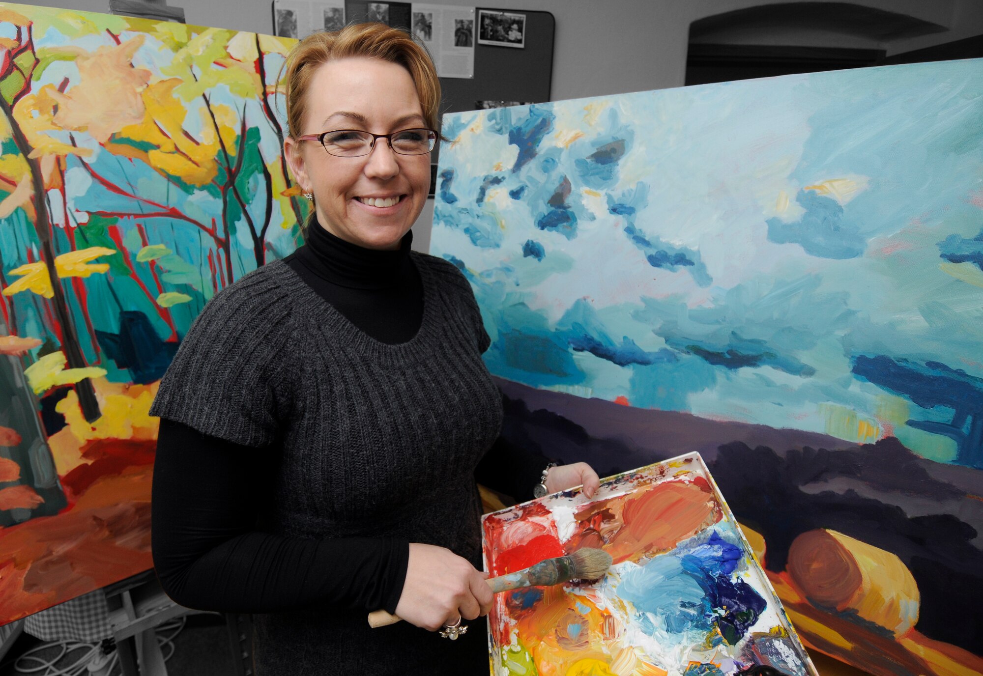 SPANGDAHLEM AIR BASE, Germany -- Chelsea Pankratz poses in front of two of her paintings Jan. 14. (U.S. Air Force photo illustration/Senior Airman Benjamin Wilson)