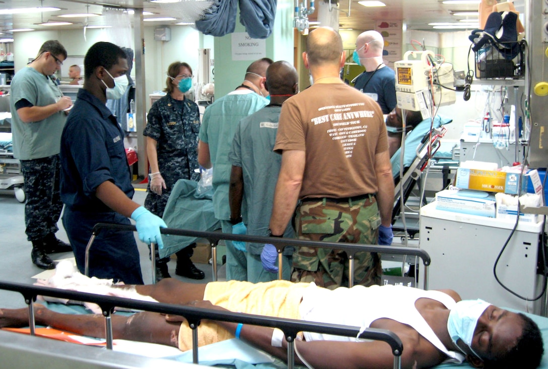 Medical personnel aboard the USNS Comfort hospital ship examine a Haitian patient, background, while another patient waits for an operating room, Jan. 21, 2010, Port-au-Prince, Haiti. The ship is in Haiti to treat patients from the Jan. 12 magnitude 7 earthquake. DoD photo by Jim Garamone