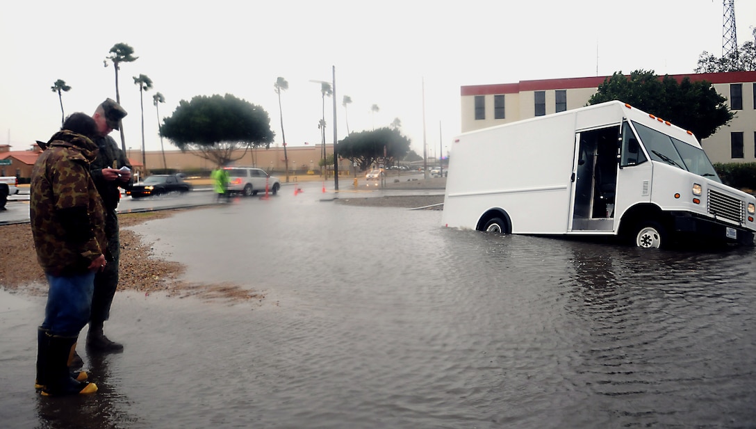 Military policeman Lance Cpl. Ian Wright helps a Base Services Department maintenance mechanic fill out an accident report after the mechanic drove his vehicle into a retention basin hidden by flood water on the corner of Shaw Avenue and Quilter Street at the Marine Corps Air Station in Yuma, Ariz., Jan. 21, 2010. Yuma was hit by a storm that dumped more than 2 inches of rain, causing flooding throughout the air station. The BSD workers pumped out the excess water to another retention basin that runs along Avenue 3E. Approximately 4.7 million gallons of water were pumped off streets and parking lots on station, according to Jerry Deppen, station facilities maintenance manager.