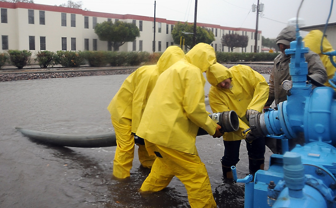 Base Services Department workers set pipes down in an overflowing water retention basin on the corner of Shaw Avenue and Quilter Street to drain the pool and retrieve a submerged vehicle at the Marine Corps Air Station in Yuma, Ariz., Jan. 21, 2010. BSD began working early against the storm that dumped more than 2 inches of rain on Yuma by pumping out the excess rainwater to nearby retention basins and Meyer Park. Approximately 4.7 million gallons of water was pumped off station streets and parking lots, according to Jerry Deppen, station facilities maintenance manager.