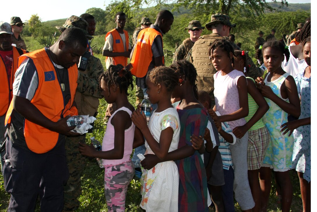 Haitian Ministry of the Interior aid workers work with Marines from Battalion Landing Team, 3rd Battalion, 2nd Marine Regiment, 22nd Marine Expeditionary Unit, to hand out supplies Jan. 21 near Cotes de Fer, Haiti. Marines and Sailors from the 22nd MEU set up a temporary relief-supply distribution point near Cotes de Fer, bringing in bottled water and food. The 22nd MEU, embarked aboard the ships of the Bataan Amphibious Ready Group, is deployed in support of relief operations in Haiti. (Official Marine Corps photo by Staff Sgt. Wayne Campbell)
