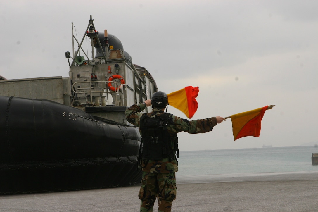 Petty Officer 3rd Class Andrew Saslow, a beachmaster with the forward-deployed Essex Amphibious Ready Group (ARG), provides hand and arm signals to a landing craft air cushion (LCAC) arriving ashore, Jan. 22. LCACs were used to load more than 170 vehicles and 450 tons of equipment from the 31st Marine Expeditionary Unit (MEU) onto the forward-deployed amphibious assault ship USS Essex (LHD 2), the forward-deployed transport dock ship USS Denver (LPD 9) and the forward-deployed dock landing ship USS Harpers Ferry (LSD 49). The MEU is scheduled to support Exercise Cobra Gold 2010 (CG ’10) as part of the Spring Patrol. CG’ 10 is a regularly scheduled joint and coalition multinational exercise hosted annually by the Kingdom of Thailand.