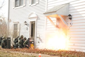 Members of the Maryland State Police Special Tactical Assault Team Element conduct a training exercise with 316th Security Forces Squadron members Jan. 19, 2010, to demonstrate protocol procedures for entering a building with potentially armed hostiles. The joint exercise, held in unusable base housing, is a means for the the 316 SFS and MDSP forces to pool experience, materials and other training techniques. The doorway explosion is the result of a simulated forced entry in the event armed inhabitants refused police access. The charge that removed the door and caused it to travel a few feet consisted of 100-grain detonation cord.