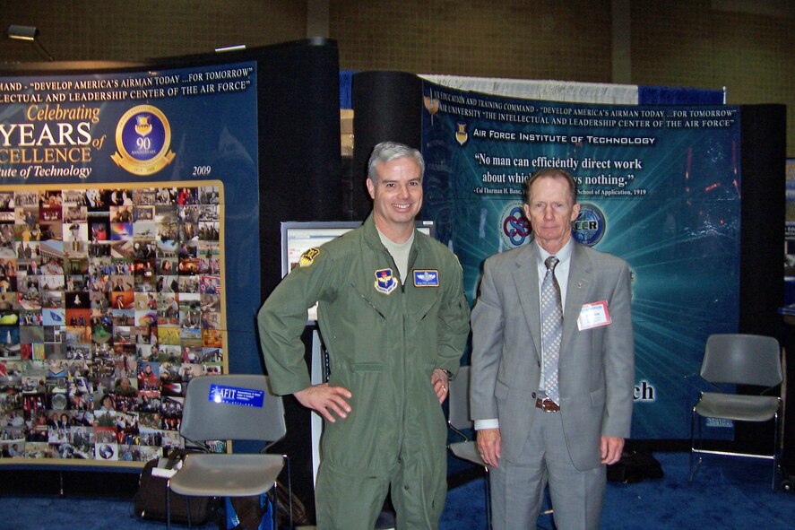 AFIT Commandant Brig Gen Walter Givhan, and the Dean of the  Graduate School of Engineering and Management, Dr Marlin Thomas, stand in front of the AFIT exhibit at the 2010 AETC Symposium.