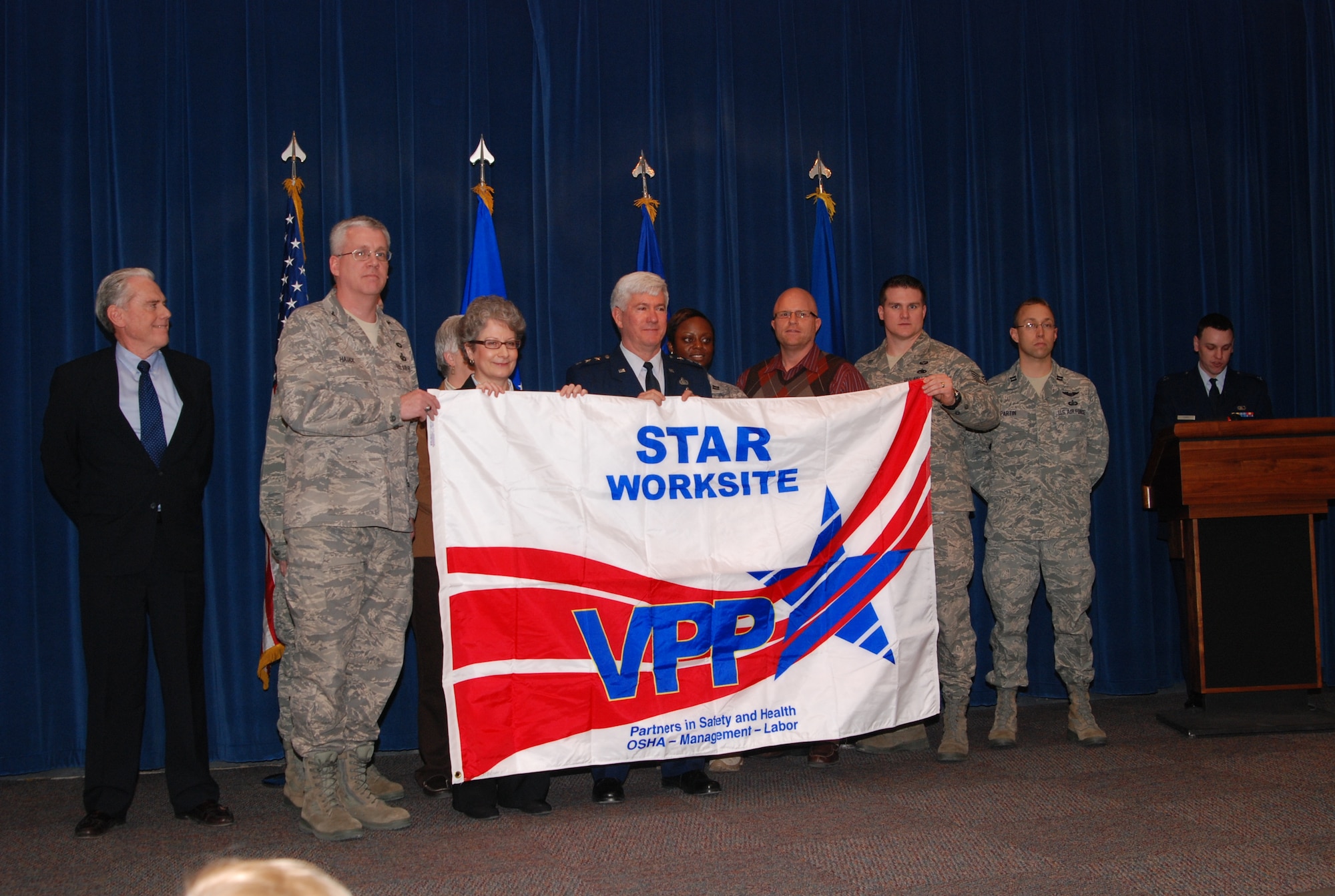 Mr Gilcrest, OSHA, Col Hauck, Ms Taylor, Ms Emery (back) OSHA, LtGen Owen, Capt Reviere, Mr. Harris, TSgt Rose, Capt Partin, Capt Ferry present the VPP Star Worksite banner. (USAF photo/Bonnie White)
