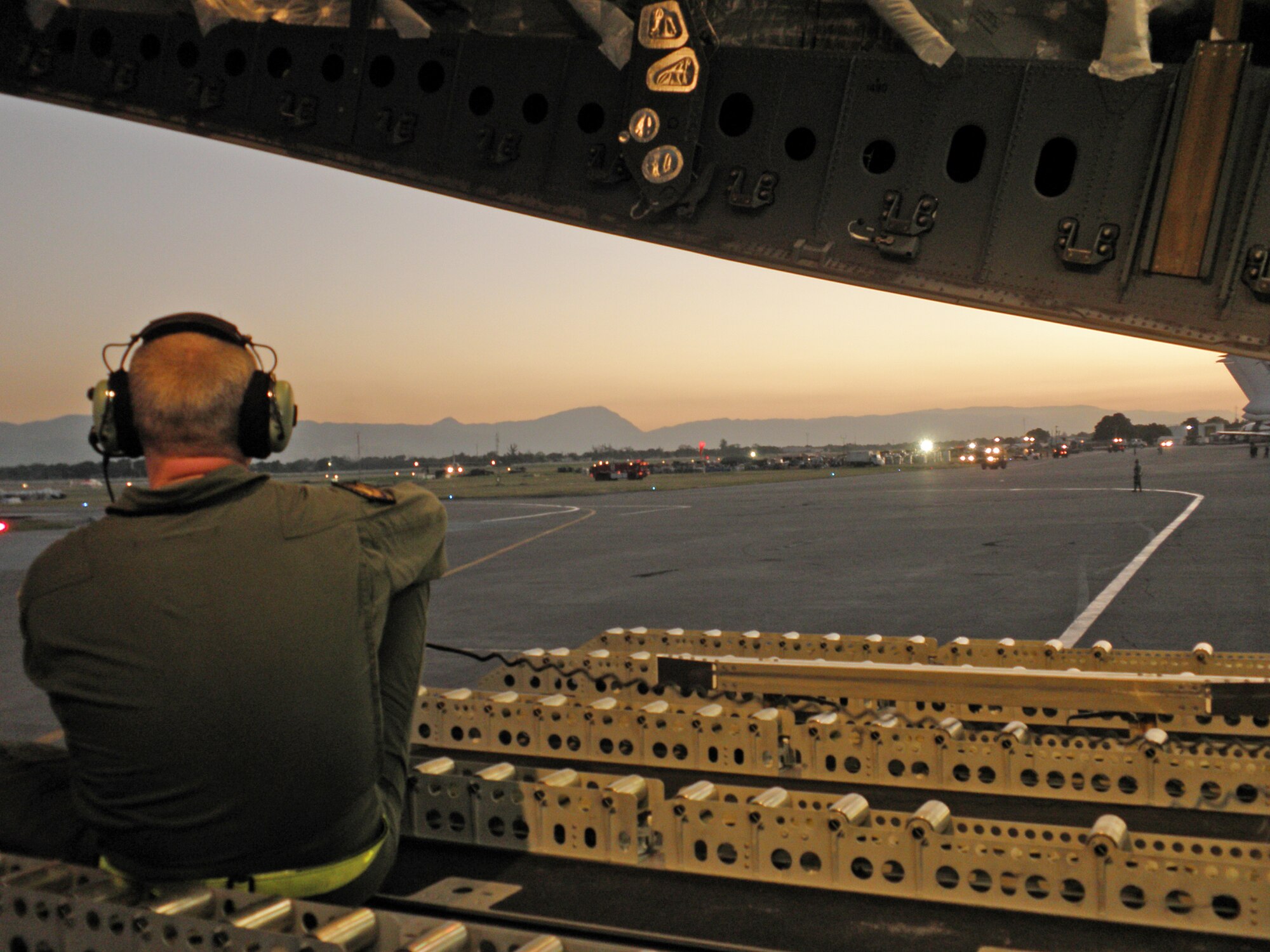 Norwegian air force 1st Lt. Jan Barre Prestbakmo gives directions to the pilot as his C-17 transport aircraft backs up in preparation for takeoff from the main airport at Port-au-Prince, Haiti, Jan. 18, 2010. The aircraft and multinational aircrew had just delivered 15 pallets of material to construct a headquarters for aid workers at the airport. The air relief is being delivered in response to a massive earthquake that struck Haiti Jan. 12, 2010. This is the first humanitarian assistance operation flown by the Heavy Airlift Wing since it stood up in July 2009. The wing is a multinational force made up of airmen from 12 nations. Lieutenant Prestbakmo is a loadmaster for the Heavy Airlift Wing out of Papa Air Base, Hungary. (U.S. Air Force photo/Tech. Sgt. Richelle Morey)