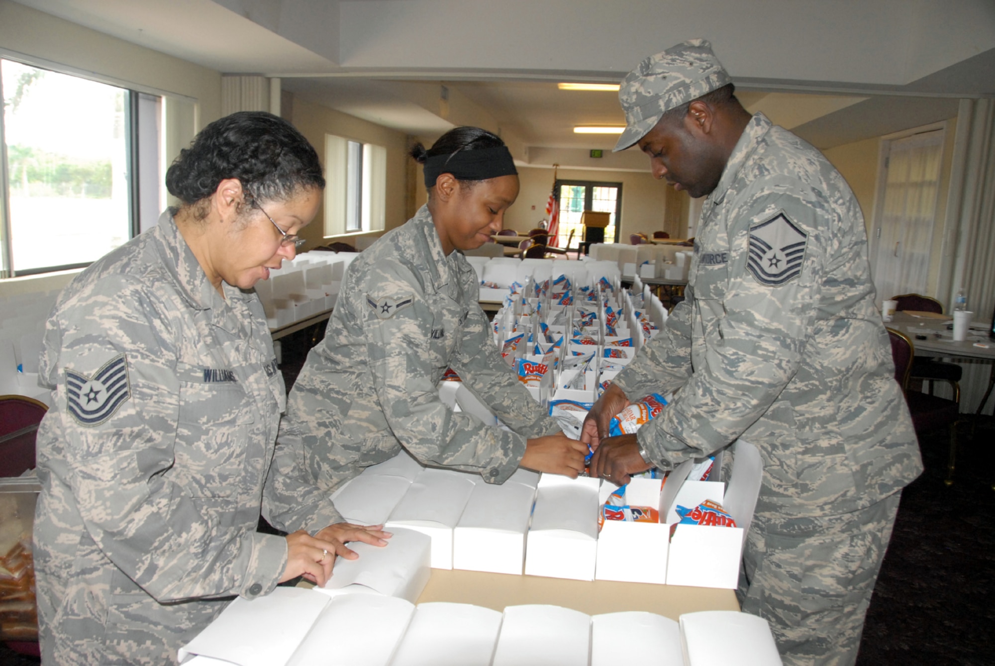 Tech Sgt. Mayra Williams and Master Sgt. Cleon McFarlane, 482nd Service's Squadron and Airman Markeya Williams, 911th Services Squadron, Pittsburgh IAP, box lunches at the Falcon's Nest Club at Homestead Air Reserve Base, Fla., as part of Operation Unified Response. The meals will be served to Hatiain evacuees being in-processed on base (Air Force photo/Master Sgt. Chance Babin)