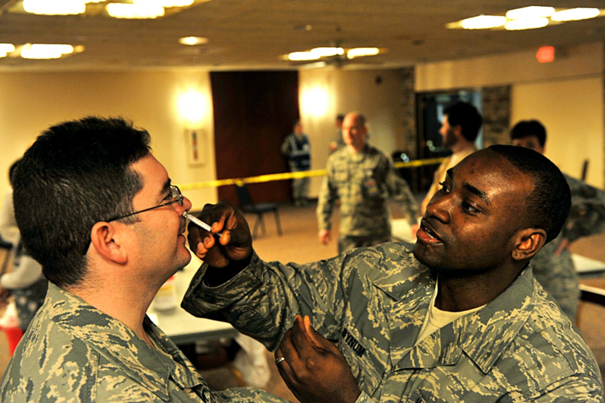 OFFUTT AIR FORCE BASE, Neb. - Master Sgt. Jesse Renteria, with the 55th Maintenance Operations Squadron, receives the H1N1 flu mist inoculation from Staff Sgt. Vashon Bynum, with the 55th Medical Group, during a Point of Distribution exercise Jan. 21 at the community center here. More than 1,000 active-duty personnel processed through the center to test the 55th Wing's ability to respond to a public health emergency.  Many received their H1N1 inoculation during the event. U.S. Air Force photo by Charles Haymond 
