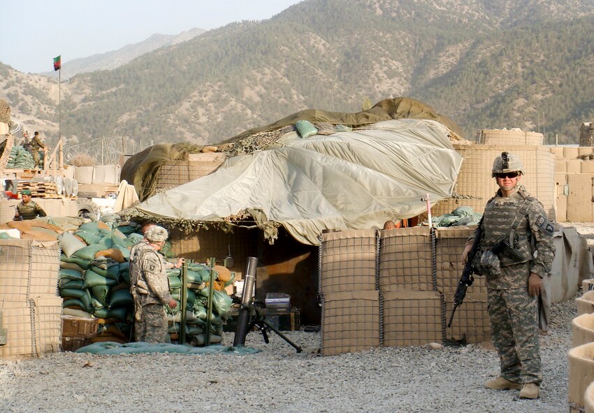 Still bloodied and bandaged (above), Capt. David Golden was able to return to duty the next day after an enemy 107 mm rocket exploded 8 feet from him at Zerok, Afghanistan, Sept. 28, 2008. At right, Golden stands in front of the mortar pit at the Zerok combat outpost where he was talking to the crew just moments before the rocket attack. He and the entire mortar pit crew were injured, but all survived and eventually returned to duty.
(Courtesy Photo)