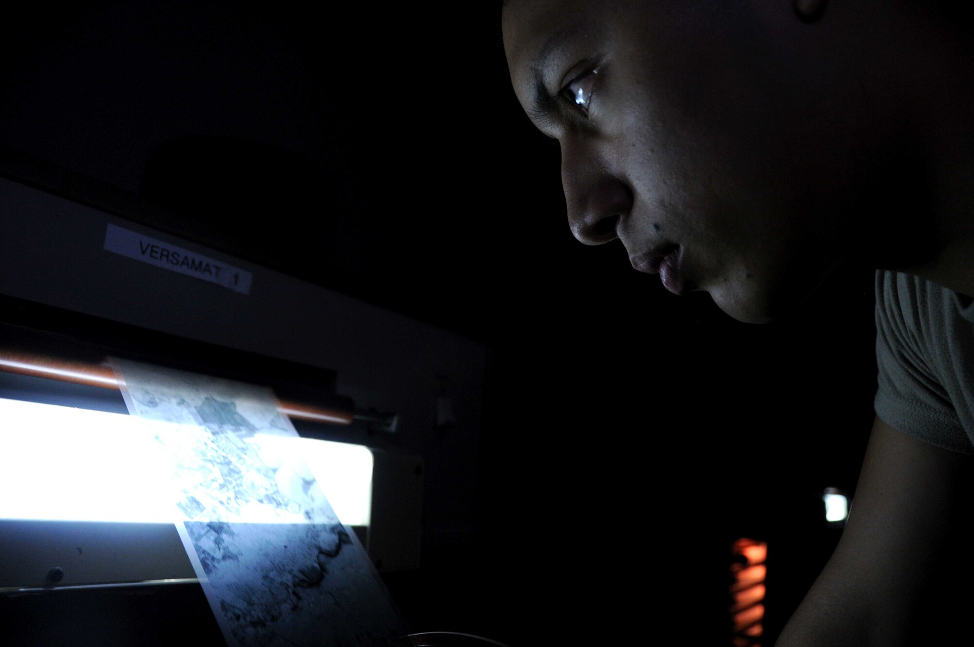 Airman 1st Class Emerson Nunez, National Air and Space Intelligence Center, inspects more than 1000 feet of processed film as it is spooled on the Versamat Jan. 16 at Wright-Patterson Air Force Base Open Skies Media Processing facility. The film was taken by an OC-135B crew of the devastation in Haiti and will be used to help coordinate recovery and relief efforts. (U.S. Air Force photo by Senior Airman Laszlo Babocsi)