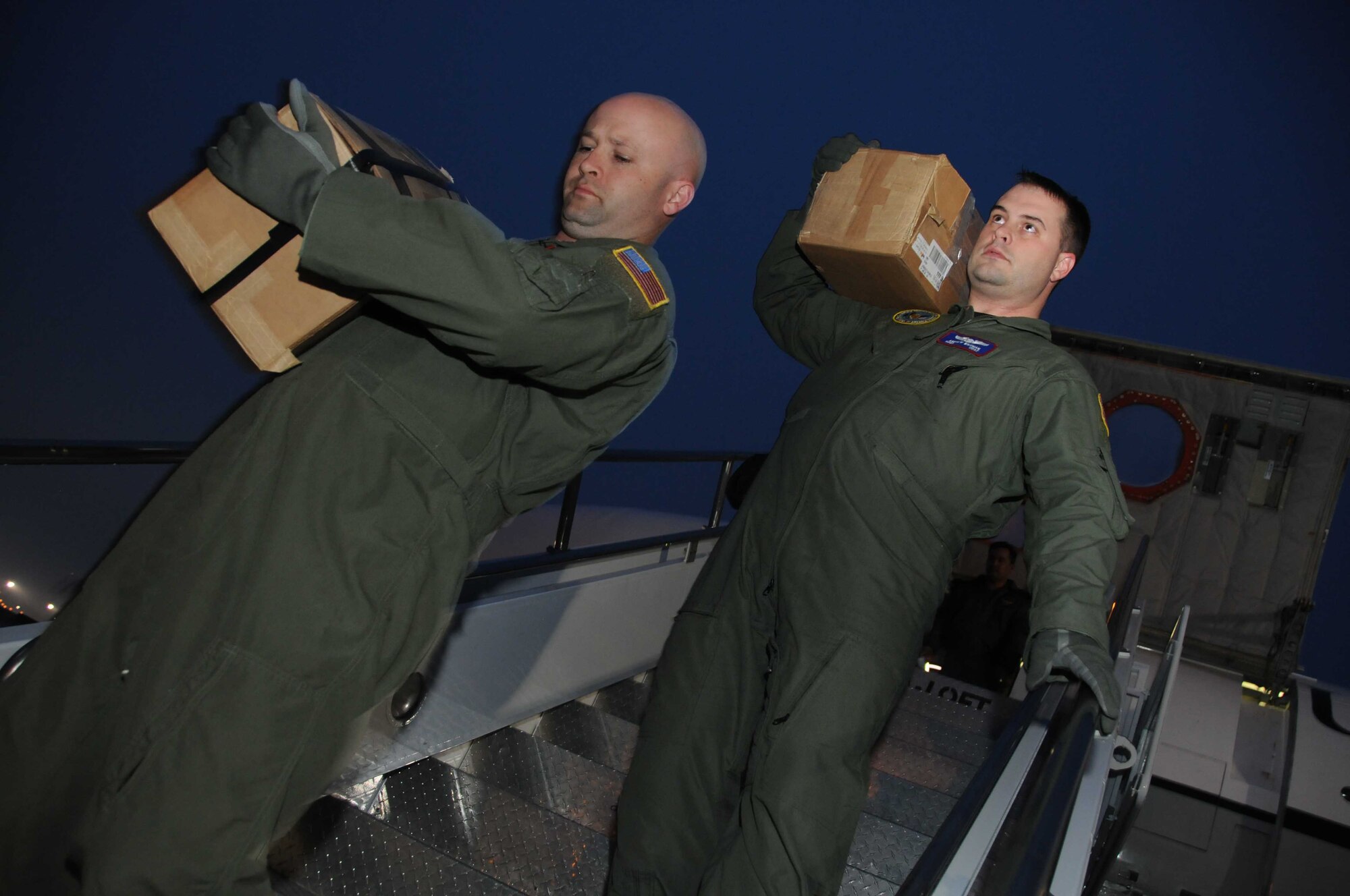 Master Sgt. Charles Duffield and Staff Sgt. Andrew Wiedman, OC-135B aircrew members, unload imaged film from an Open-Skies aircraft at Wright-Patterson Air Force Base Jan. 16. The crew was returning to the airfield after flying and imaging aerial film of the devastation in Haiti. The mission provides detailed imagery for damage assessment to assist in recovery and relief efforts. (U.S. Air Force photo by Senior Airman Laszlo Babocsi)