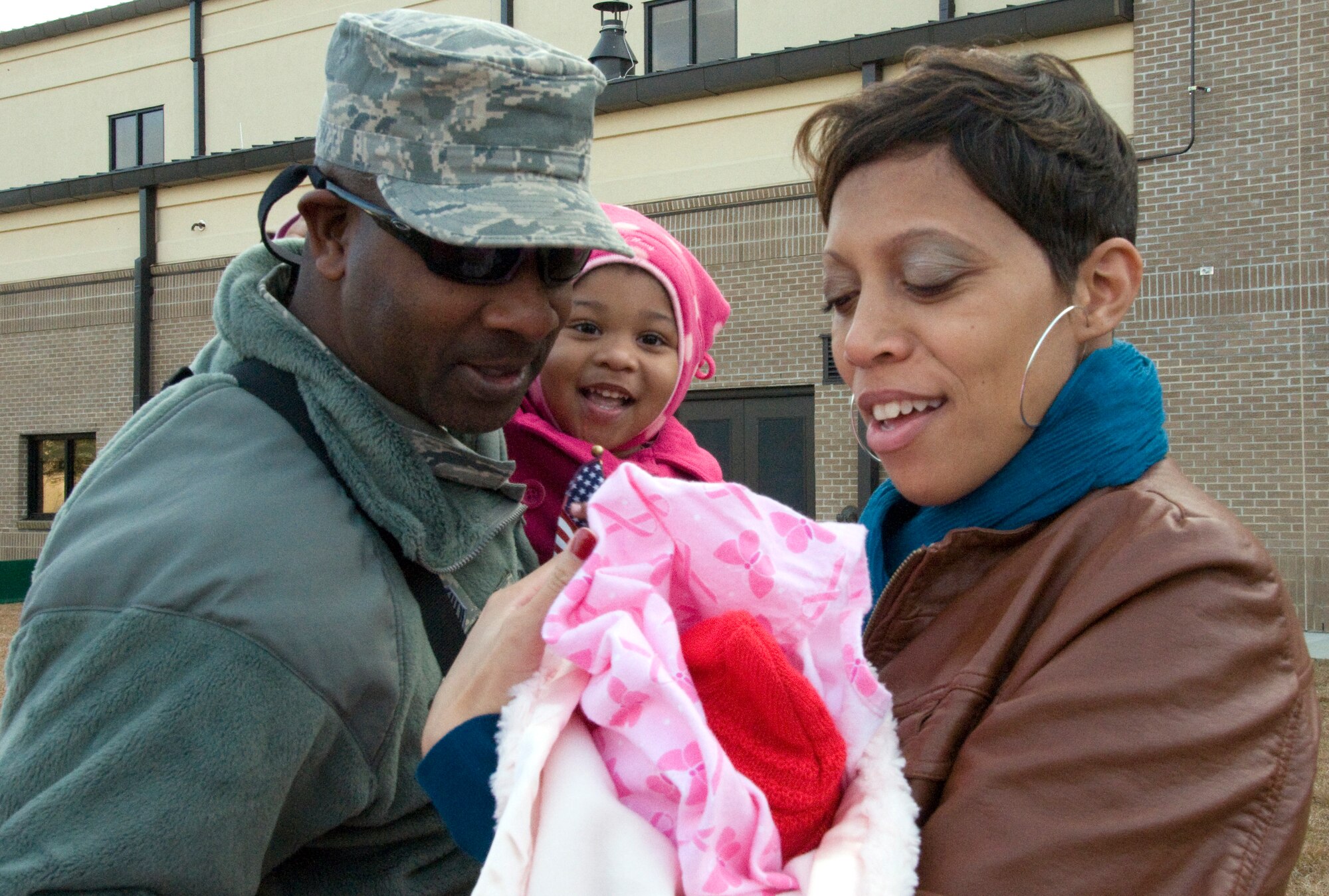 Master Sgt. Kermit Watson, a firefighter with the 403rd Civil Engineer Squadron, meets his newborn daughter Nylah Grace for the first time on Jan. 17 while his fiancee Shantel Wilder and her daughter Madison look on. Sergeant Watson arrived with the first group of returning deployers to a large welcome home reception. (U.S. Air Force Photo by Senior Airman Kimberly Erickson)