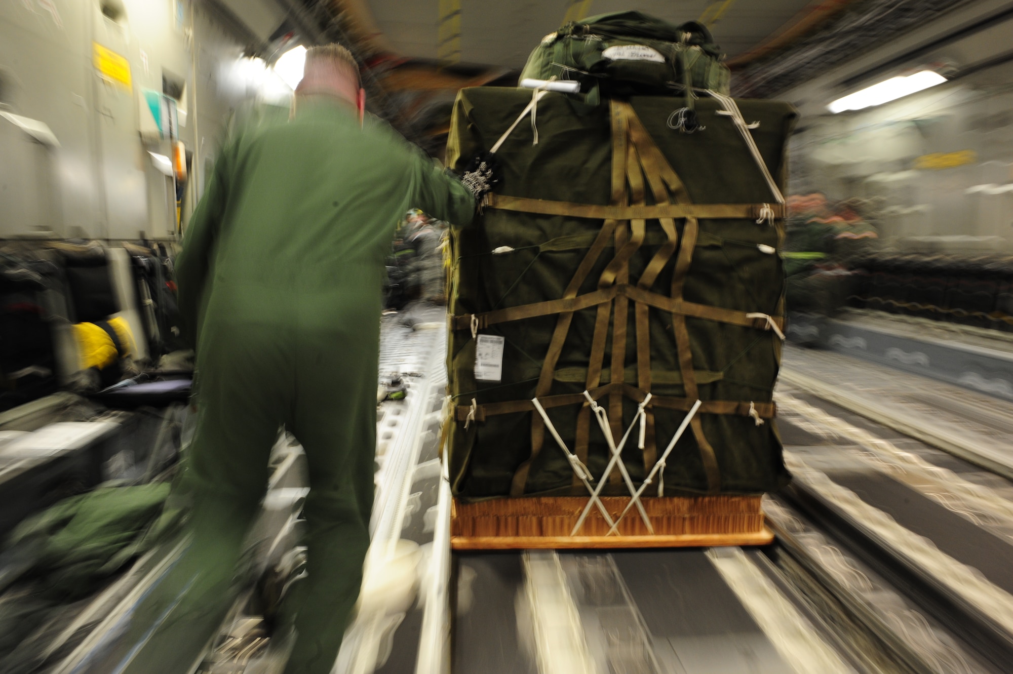 U.S. Air Force Staff Sgt. Matthew Shields, a C-17 Globemaster III loadmaster assigned to the 15th Airlift Squadron, Charleston Air Force Base, S.C., loads container delivery system bundles aboard a Charleston AFB C-17 at Pope AFB, N.C., before an air delivery mission in support of Operation Unified Response Jan. 21, 2010. The crew delivered 40 container delivery system bundles totaling 67,800 pounds of Meals Ready to Eat and bottled water. (U.S. Air Force photo by Staff Sgt. Jacob N. Bailey/Released)