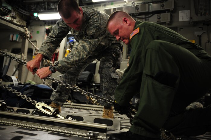 U.S. Air Force Senior Airman Justin Elliot, 43rd Security Forces Squadron, Pope Air Force Base, N.C., assists Senior Airman Mike Solly, a C-17 Globemaster III loadmaster from the 15th Airlift Squadron, Charleston Air Force Base, S.C., while configuring an aircraft for an air delivery mission in support of Operation Unified Response Jan. 20, 2010. Pope AFB acted as a staging point for the Charleston AFB C-17 aircrew as they carried out the air delivery mission. (U.S. Air Force photo by Staff Sgt. Jacob N. Bailey / Released)