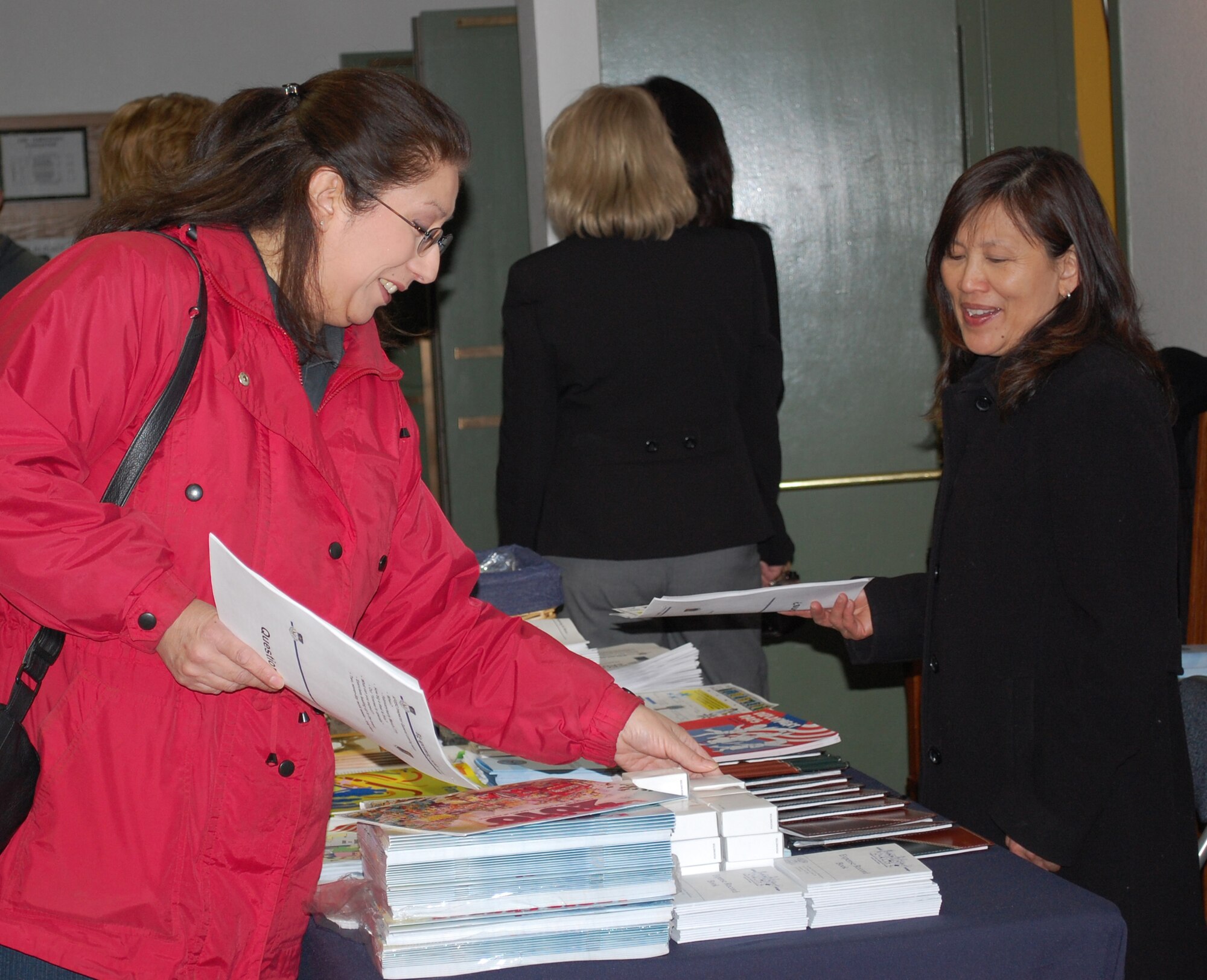 Elaine Frankhouser, left, helps herself to informational material provided by the Airman and Family Readiness Center for the Spouse's Call Jan. 14. A&FRC employee Memosa O'Dell assists her with finding pertinent documents. (U.S. Air Force photo/Valerie Mullett)