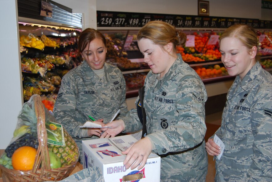 Airmen 1st Class Brittany Musha and Courtney Taylor, and Airman Jasmine Staup guess the weight of a box of Idaho potatoes in an effort to win a fruit basket compiled by the base commissary at the nutritional information session on Jan. 13. Airman Jasmine Staup won the prize. (U.S. Air Force photo/Airman 1st Class Kristina Overton)
