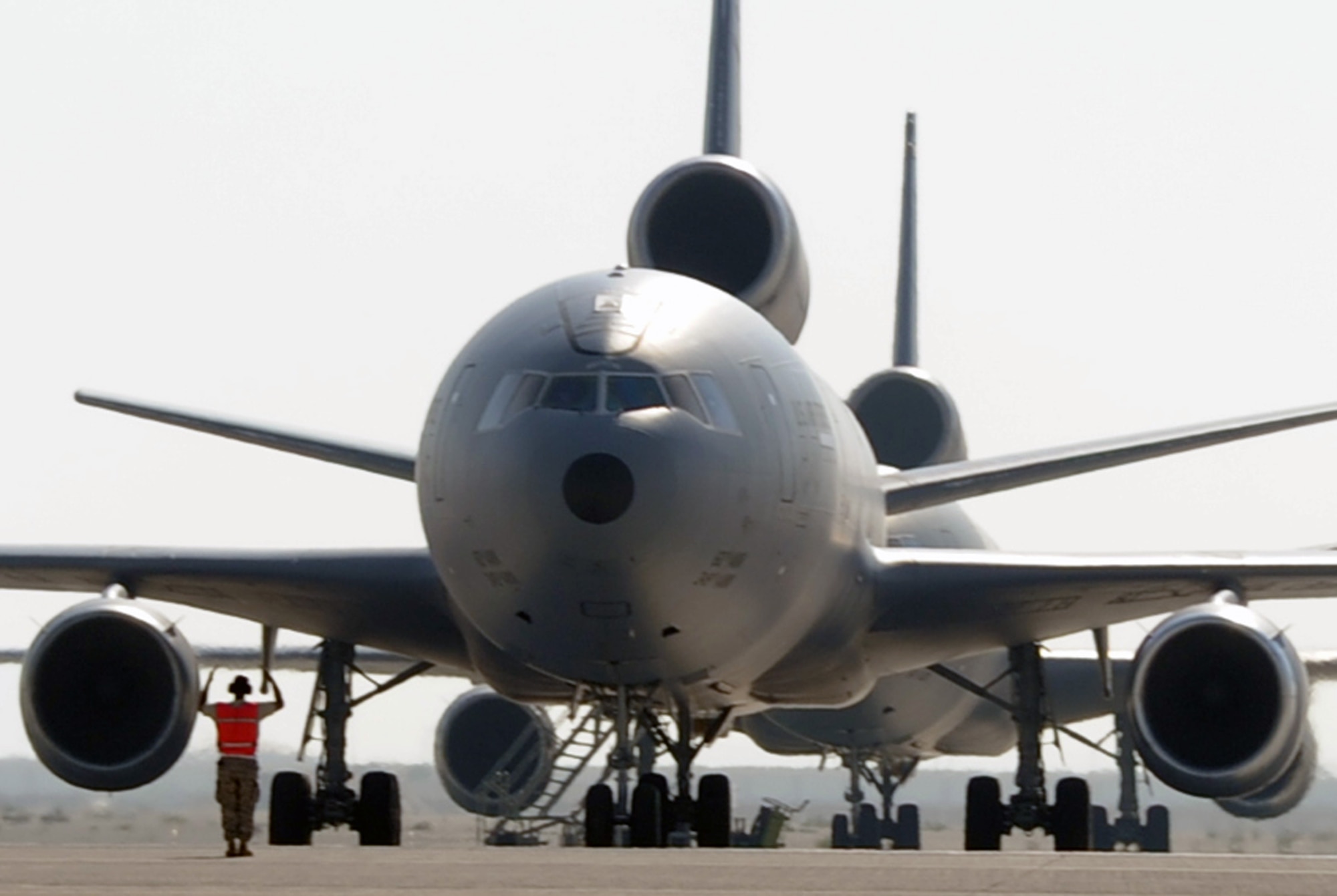 A maintenance Airman directs a KC-10 Extender from its parking area as the plane moves out for a combat air refueling mission during operations on the flightline at a non-disclosed base in Southwest Asia on Jan. 22, 2009. The KC-10, assigned to the 908th Expeditionary Air Refueling Squadron and deployed from Joint Base McGuire-Dix-Lakehurst, N.J., is one of Air Mobility Command's air refueling aircraft deployed to the U.S. Central Command area of responsibility that provides the "global reach" for Air Force and Department of Defense aircraft through air refueling operations for Operations Iraqi Freedom and Enduring Freedom and the Combined Joint Task Force-Horn of Africa. (U.S. Air Force Photo/Tech. Sgt. Scott T. Sturkol/Released)
