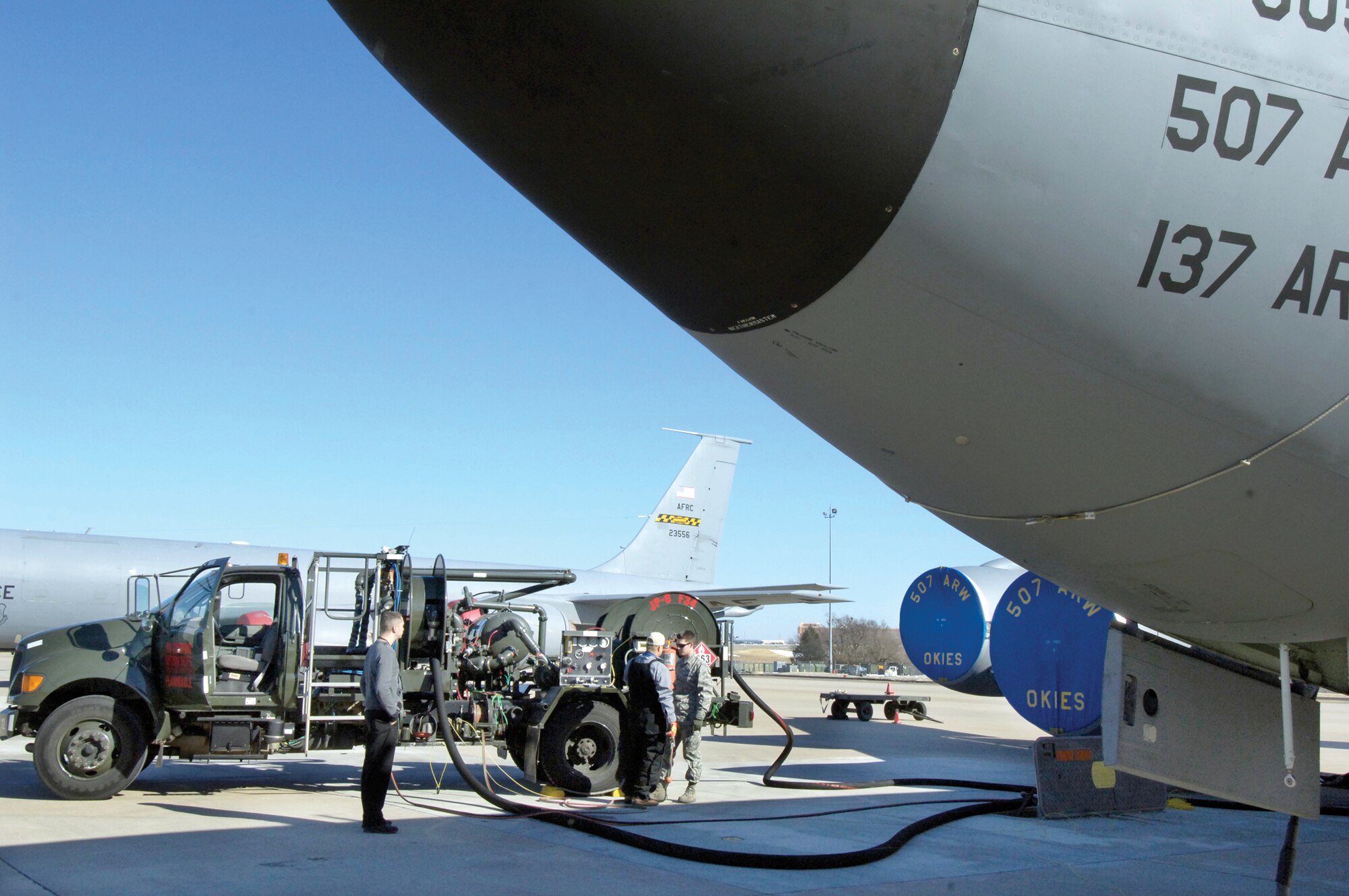 A KC-135 is prepared for refueling on the 507th Air Refueling Wing’s ramp recently.  The R-12 vehicle acts as a hydrant system, pumping JP-8 from the storage tank and refueling the aircraft faster than bringing in several trucks could. Fuels Quality Flight quality assurance evaluator Joshua Morris, far left, watches the procedure as Base Fuels’ Richie Richter and Airman 1st Class Daniel Balla of the 507th Air Refueling Wing finish the hook ups. (Air Force photos by Margo Wright)