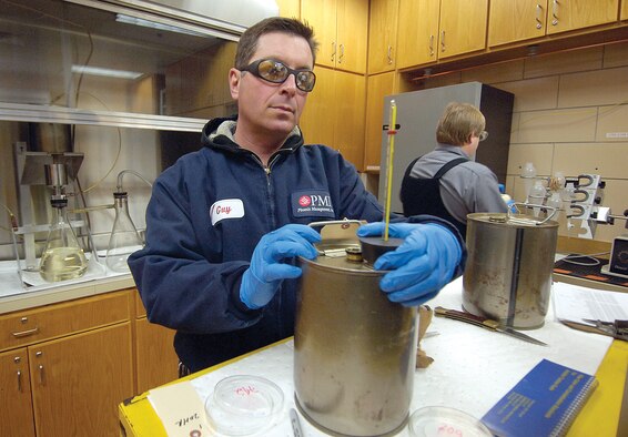 In an on-base lab, technicians scrutinize and test aviation fuel coming into Tinker and several times before it reaches an aircraft’s tanks. “It’s vital to the safety of an air crew and aircraft to have clean and dry fuel,” said Guy Wilson, foreground. Fuel must be room temperature to test so Mr. Wilson checks the thermometer in a sample while Chris Albrecht, background, performs other checks. Filters and tests reveal the weight of the fuel and how much water or contaminants may be present. Both men are with the 72nd Logistics Readiness Squadron’s Base Fuels Quality Assurance Office. (Air Force photos by Margo Wright)