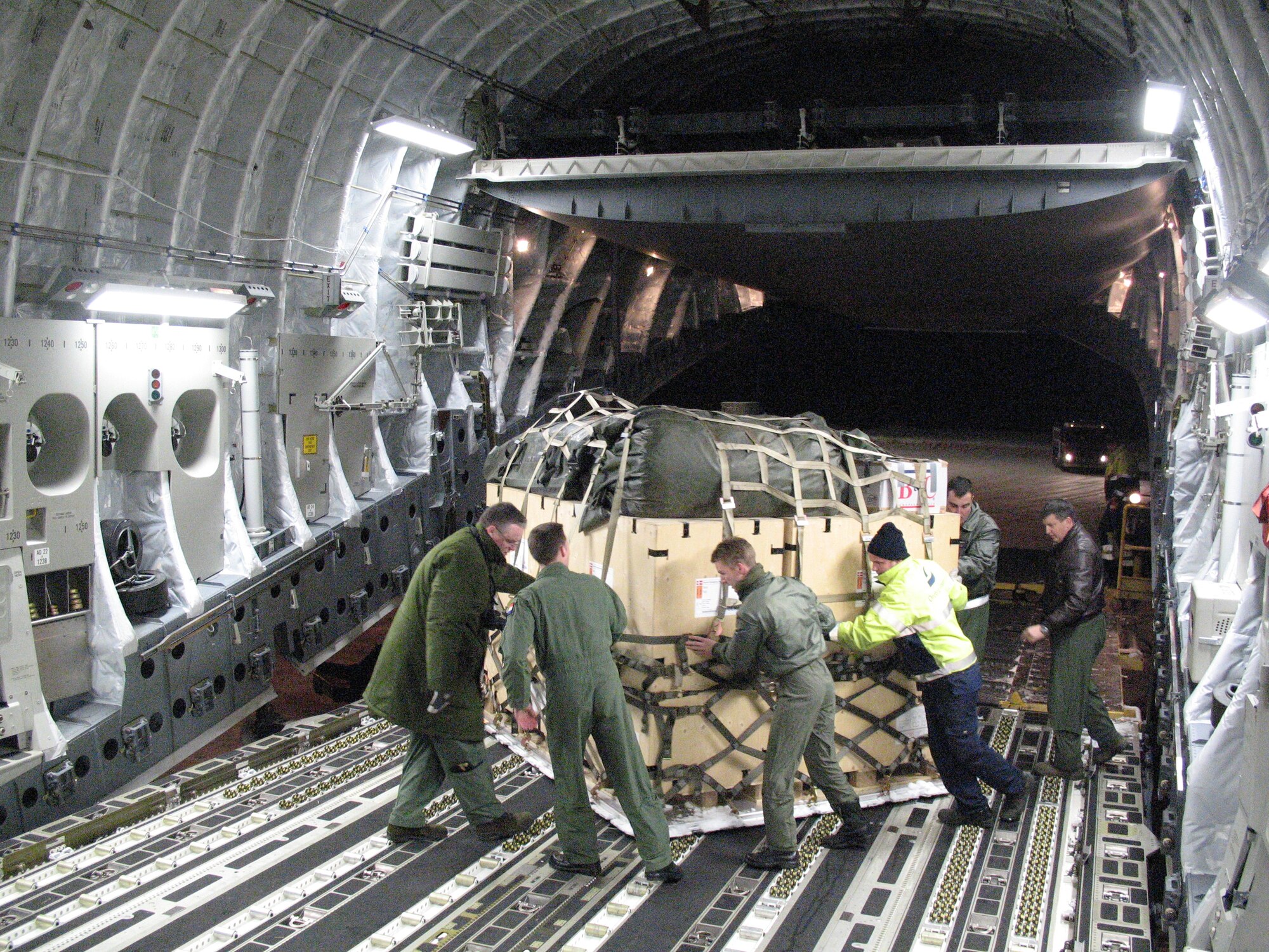 A multi-national aircrew from the Heavy Airlift Wing out of Papa Air Base, Hungary, loads a C-17 transport aircraft with aid supplies and equipment coming out of Orebro, Sweden, for its second mission to Port-au-Prince, Haiti. The first load of materials was delivered by the aircraft and its aircrew Jan. 18 to Port-au-Prince?s main airport. The air relief is being delivered in response to a massive earthquake that struck Haiti Jan. 12. This is the first humanitarian assistance operation flown by the Heavy Airlift Wing since it stood up in July 2009.  The wing is a multi-national force made up of Airmen from 12 nations.  (U.S. Air Force photo by Staff Sgt. Michael T. McCool)  