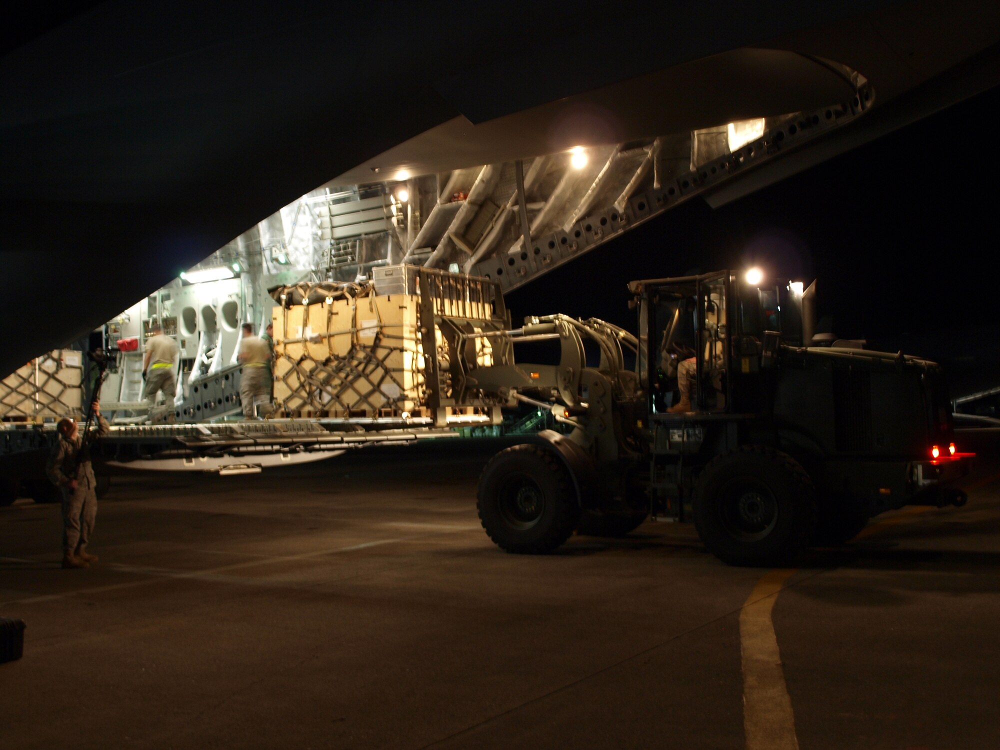 Airmen already present on the ground at Port-au-Prince?s main airport help a multi-national aircrew flying out of the Heavy Airlift Wing, Papa Air Base, Hungary, unload a C-17 transport aircraft Jan. 18.  The C-17 delivered 15 pallets of material to construct a headquarters for aid workers at the airport. Port-au-Prince is the capital of Haiti, the island nation hit by a massive earthquake Jan. 12. This is the first humanitarian assistance operation flown by the Heavy Airlift Wing since it stood up in July 2009.  The wing is a multi-national force made up of Airmen from 12 nations.  (U.S. Air Force photo by Technical Sgt. Richelle Morey)  