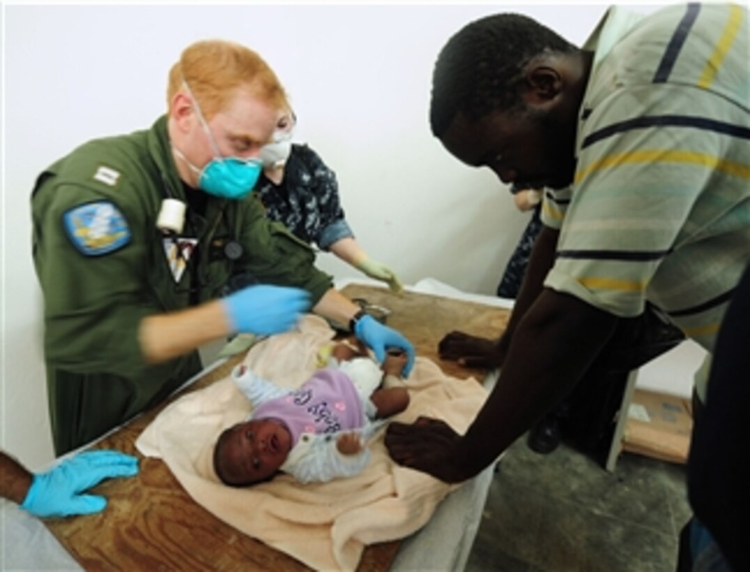 U.S. Navy sailors assigned to the aircraft carrier USS Carl Vinson (CVN 70) treat a baby injured by an earthquake as the child’s father watches in Port-au-Prince, Haiti, on Jan. 17, 2010.  The ship and Carrier Air Wing 17 are conducting humanitarian and disaster relief operations as part of Operation Unified Response after a 7.0-magnitude earthquake caused severe damage on Jan. 12, 2010.  