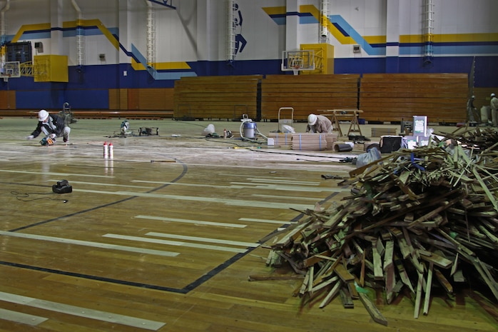 Station facility employees work to refurbish the sports court floor at the IronWorks Gym here Jan. 22. The sports court is scheduled to be ready for use Feb. 22.