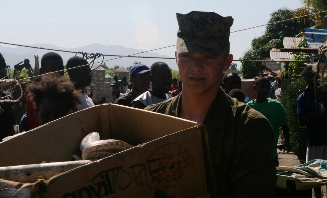 Lance Cpl. Garrett Rice, amphibious assault vehicle platoon, 22nd Marine Expeditionary Unit, helps clear a box of trash from a destroyed house in Haiti.  Marines with the Security Cooperation Marine Air Ground Task Force, Africa Partnership Station 10, spent the morning helping the surrounding community move damaged structures and clean up piles of rubble to improve living conditions for the Haitians after an earthquake devastated their country, Jan. 12.