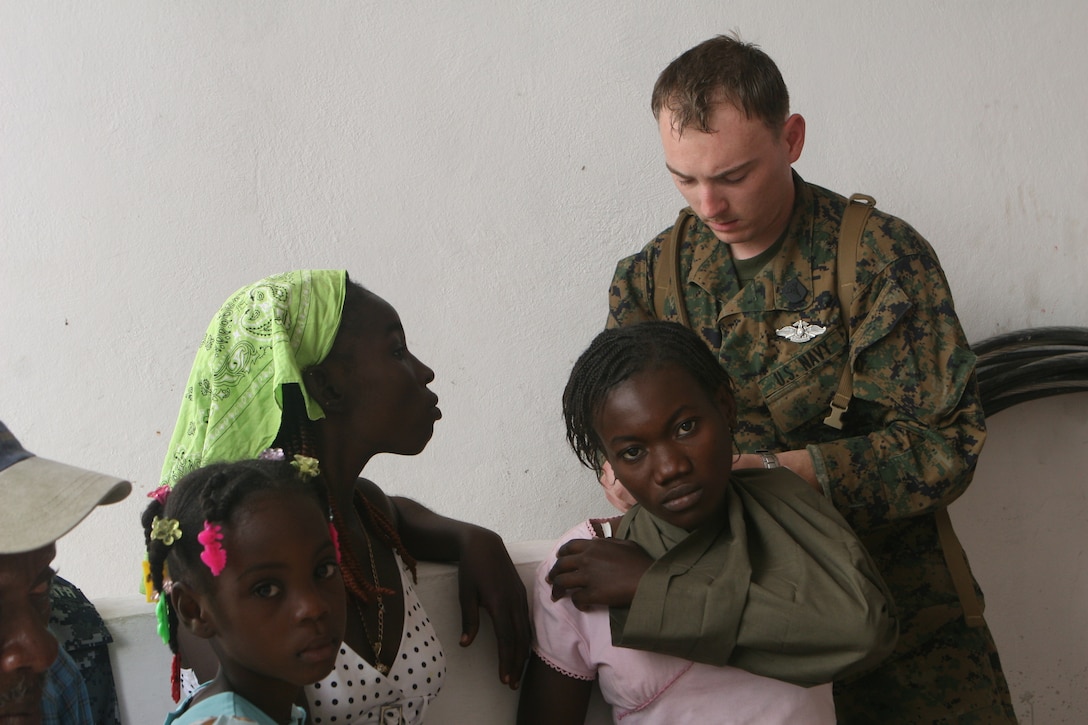 Petty Officer 3rd Class Barry Carr, a Corpsman with the Security Cooperation Marine Air Ground Task Force, Africa Partnership Station 10, offers medical assistance to a group of Haitians.  Marines and Sailors from the SCMAGTF offered their assistance to support locals in dire need of medical treatment after a devastating earthquake struck the island, Jan. 12.
