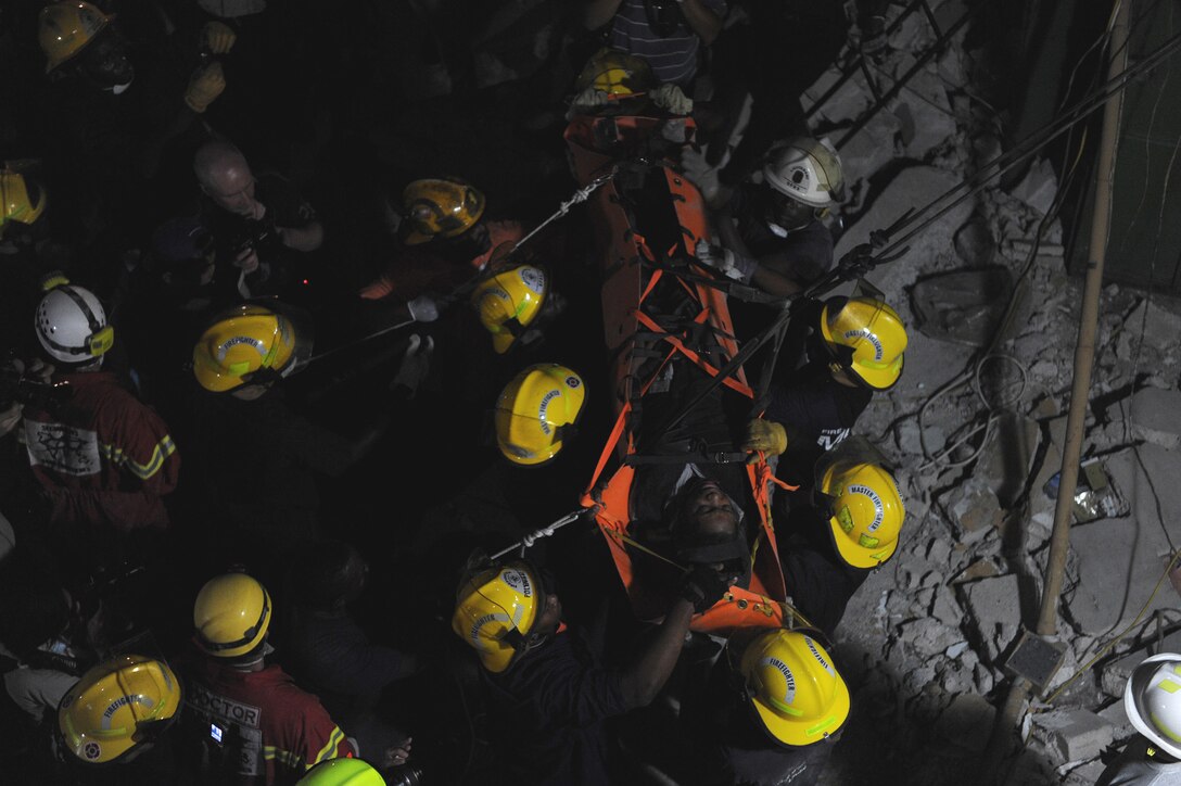 Members of various rescue teams, including U.S. Air Force pararescuemen from the 23rd Special Tactics Squadron at Pope Air Force Base, N.C., lower a 25-year-old woman after freeing her from a space in a collapsed building Jan. 19, 2010, in Port-au-Prince, Haiti. The woman was trapped for seven days. (U.S. Air Force photo/Tech. Sgt. James L. Harper Jr.)
