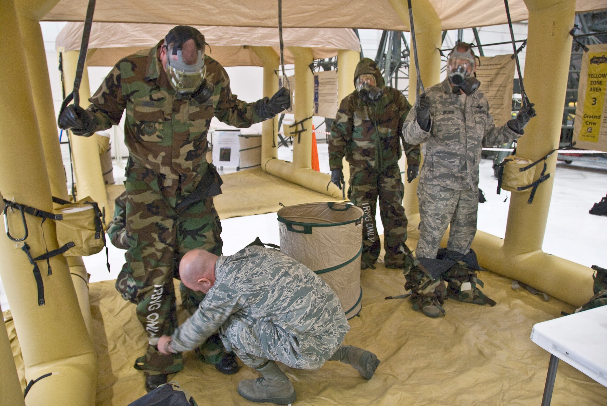 An instructor demonstrates the proper way to remove contaminated outergarments after exposure to simulated chemical agents during at ASTO exercise in the Main Hangar of the Kentucky Air National Guard Base in Louisville, Ky., on Dec. 12, 2009. (United States Air Force by Senior Airman Maxwell Rechel)

