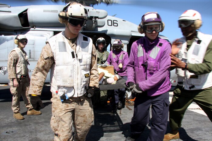 Marines and Sailors of the 24th Marine Expeditionary Unit and Nassau Amphibious Ready Group carry a 2 year-old off an MH-60 Seahawk during an emergency medivac of Haiti nationals Jan. 23, 2010. The medivac consisted of airlifting four Haiti nationals, two men and two children from USNS Comfort and transporting them to USS Nassau where they received further medical care. One adult male is currently in critical condition, the other has an open fracture on his left leg and is currently in stable condition. The two-year-old child is in stable condition, and one infant had no apparent wounds. The 15 minute flight, estimated arrivedl  in the early afternoon and Marines and Sailors responded immediately. (U.S. Marine Corps photo by Lance Cpl. David J. Beall)